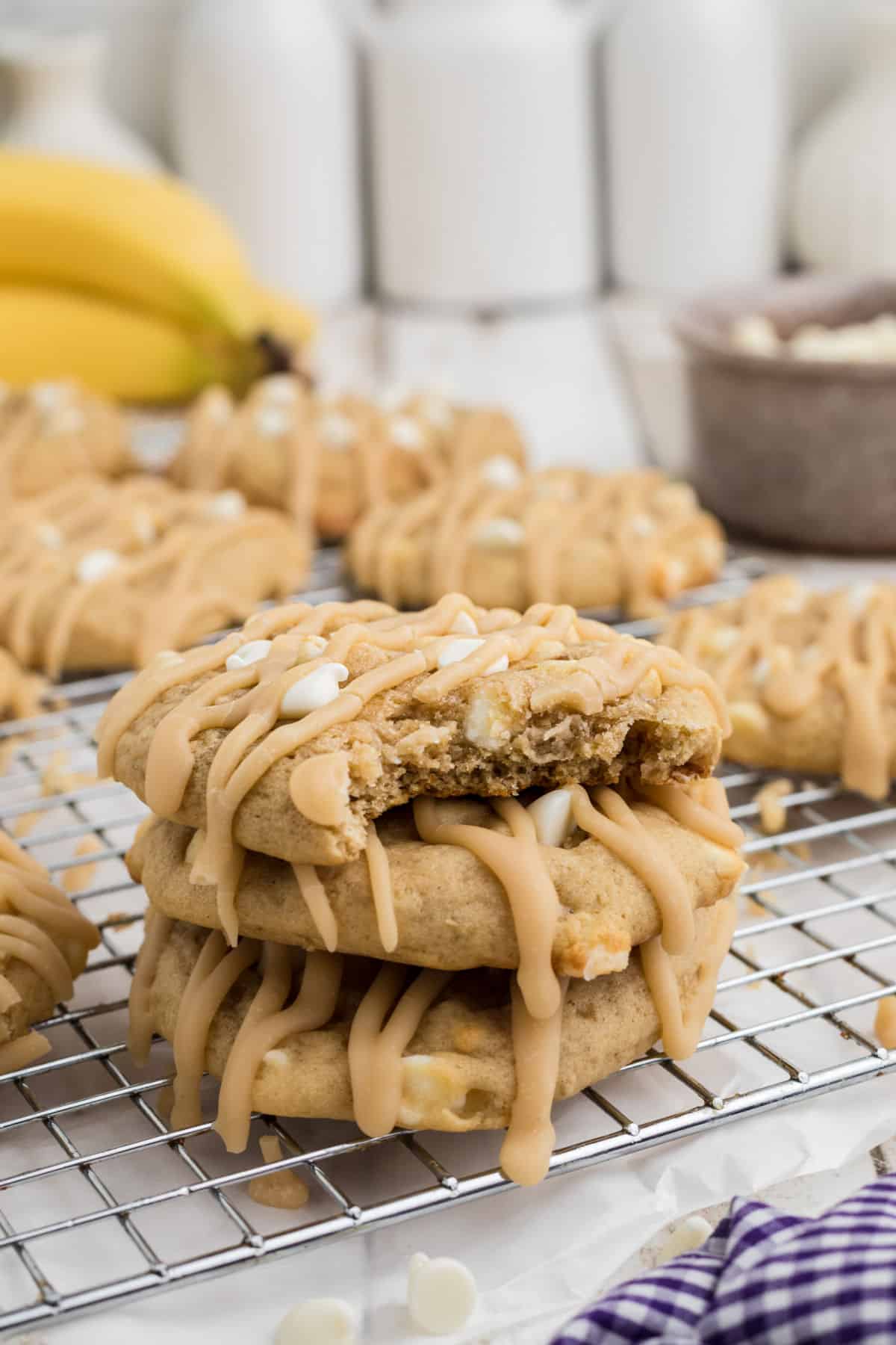 A side angle shot of a stack of bananas foster cookies with a bite taken.
