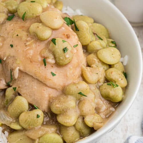 Close up of a bowl of chicken and lima beans on rice.
