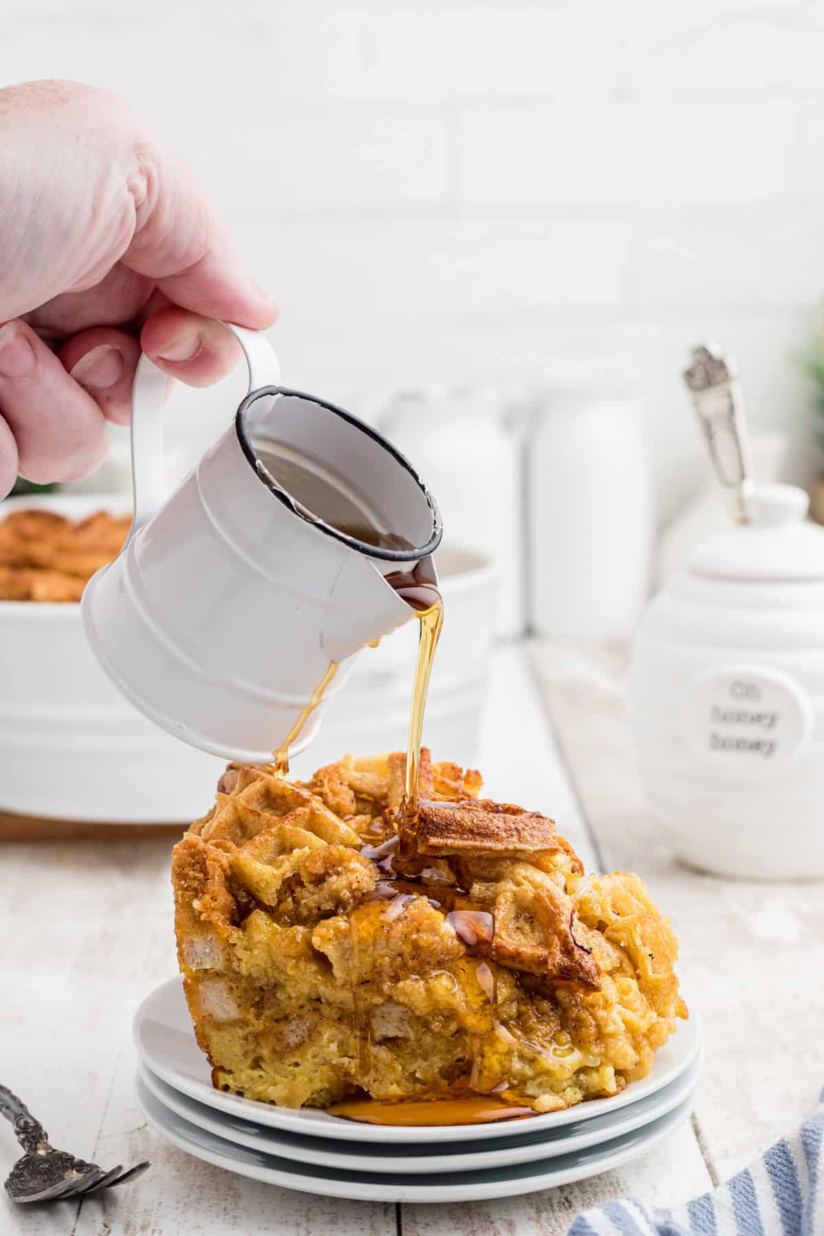 Syrup being poured over a piece of chicken and waffle casserole.