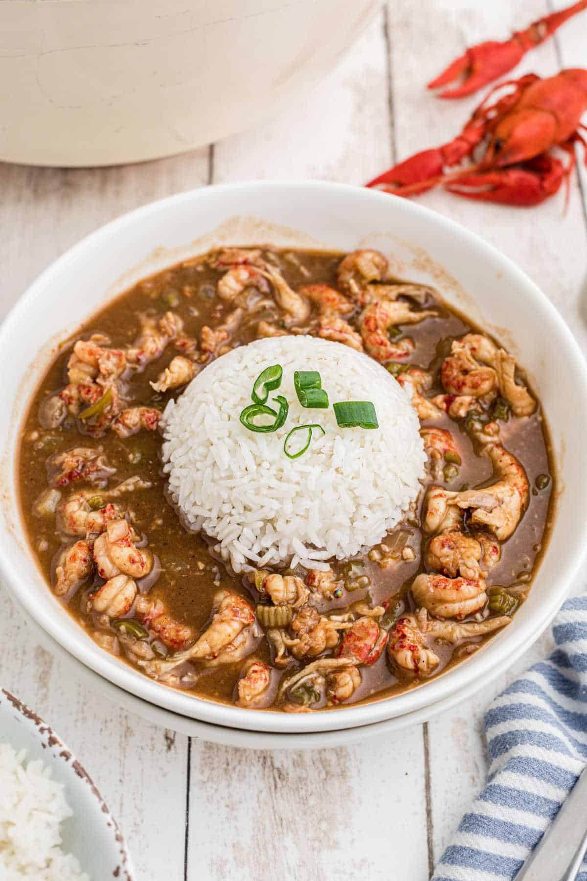 A bowl full of crawfish stew with a heap of rice in the middle.