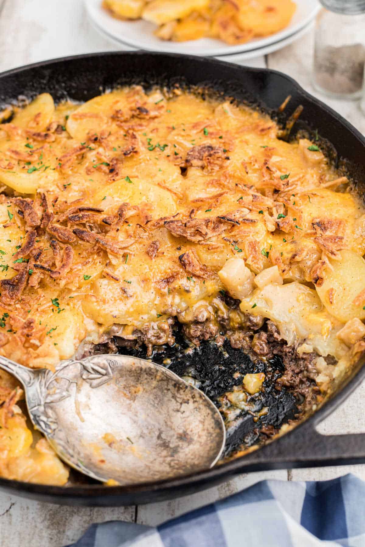 A skillet with a spoon in it, with hobo casserole.