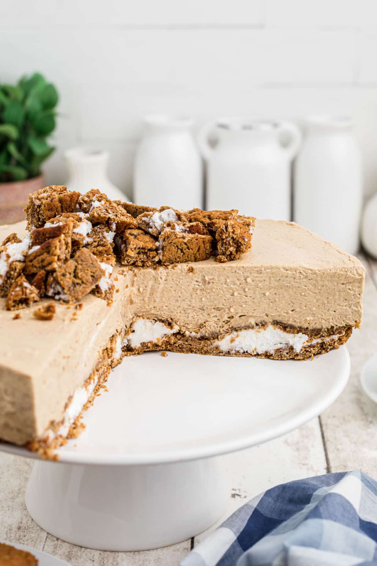 A cake stand with an oatmeal creme pie cheesecake with slices removed.