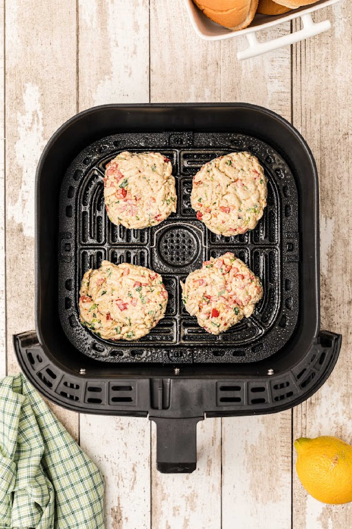 Four crab patties in an air fryer drawer.