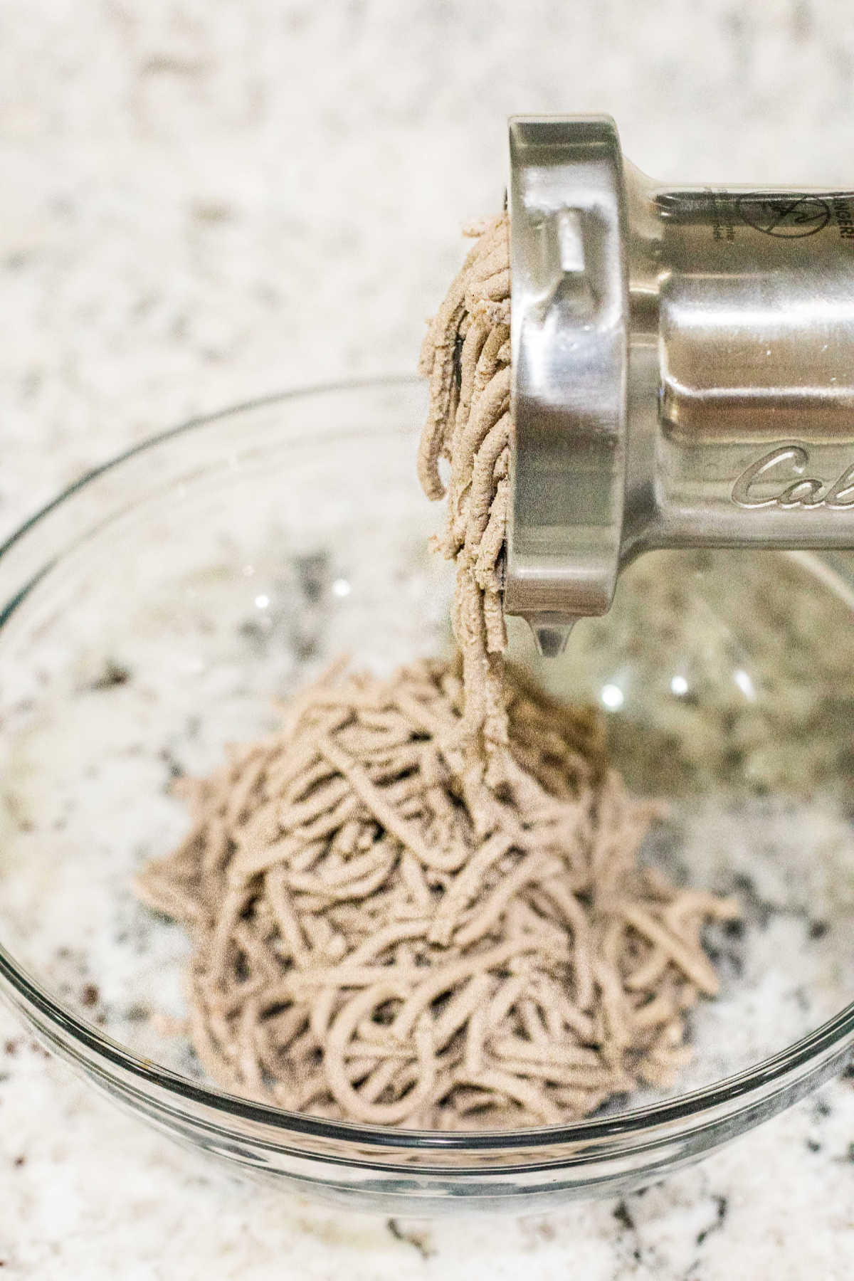 A meat grinder attachment, grinding meat and other ingredients to make boudin sausage.