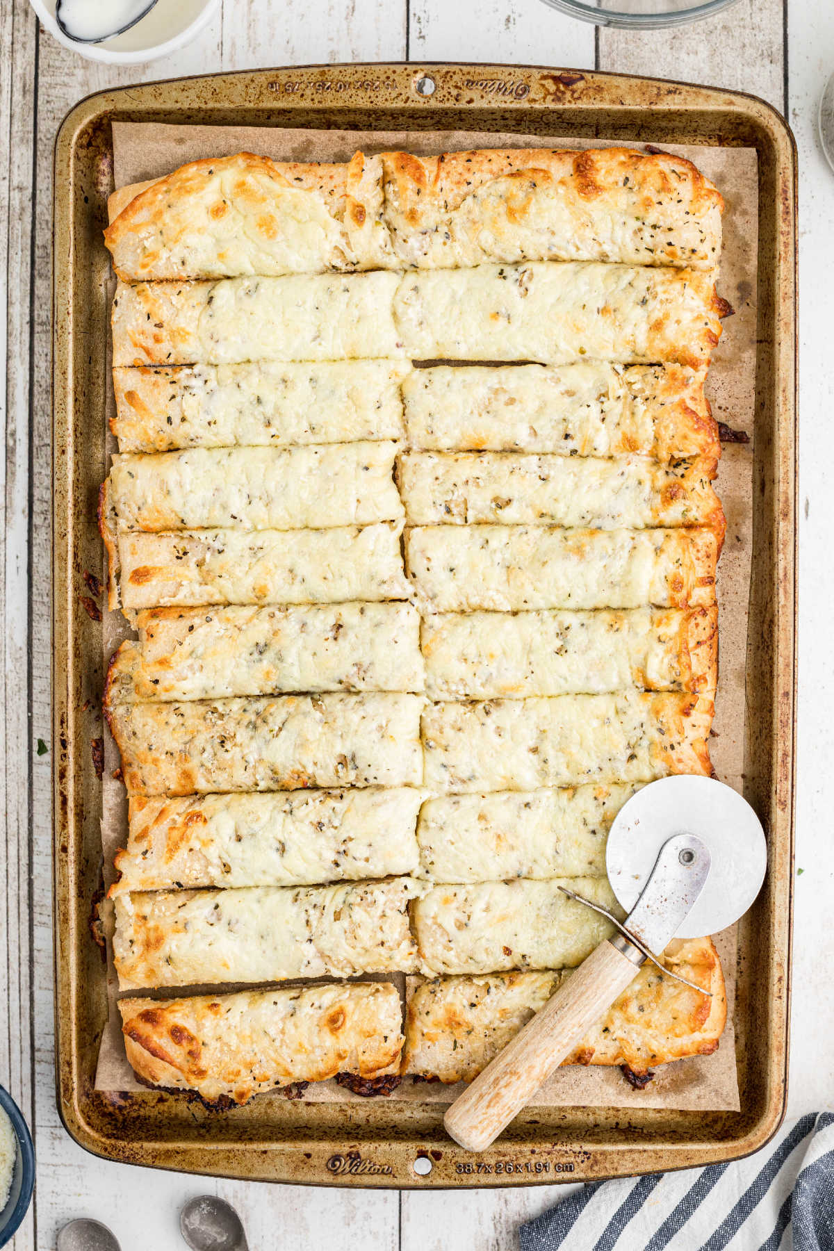 A cheesy bread that has been cut into rectangles with a pizza wheel.