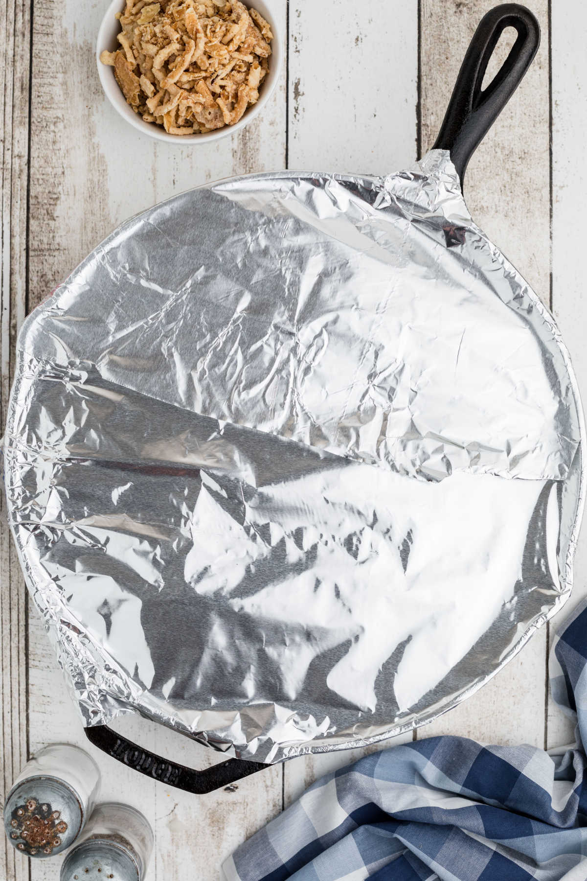 Overhead view of a black skillet covered with foil.
