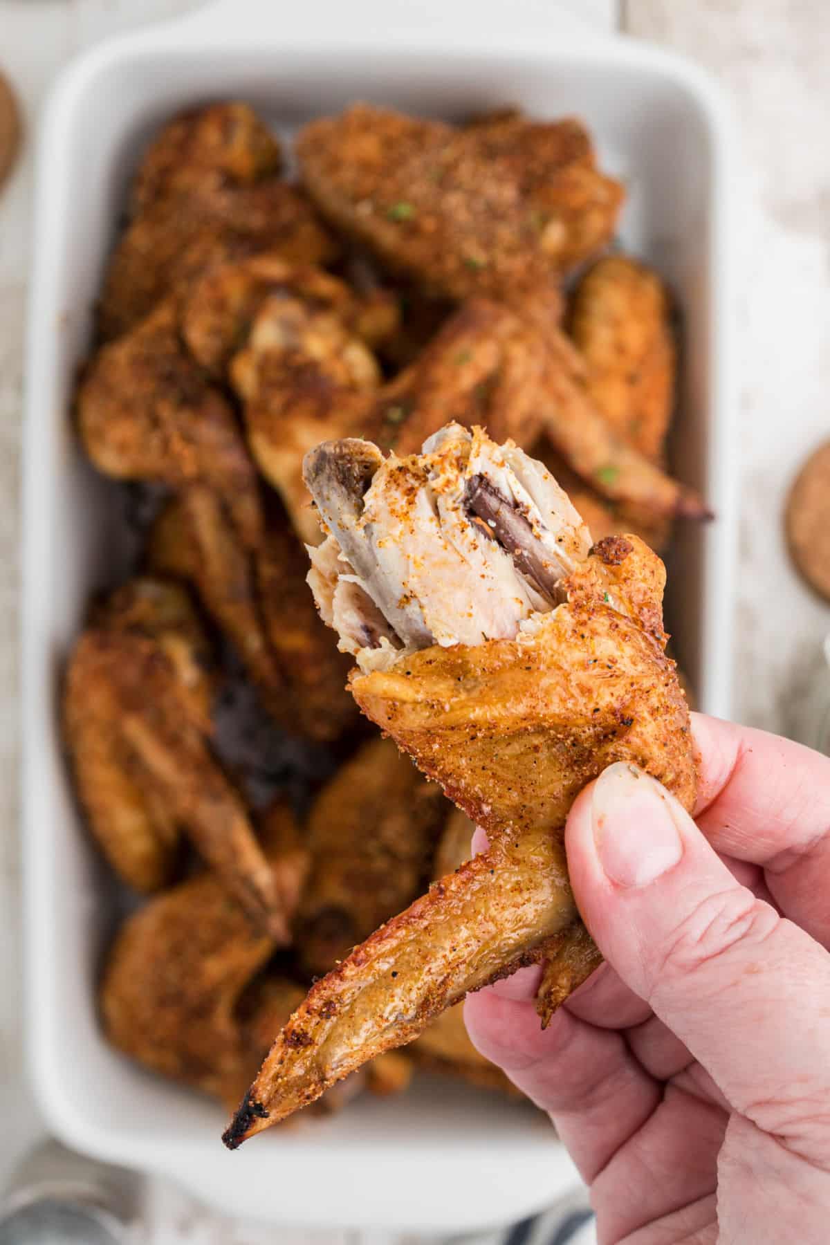A wing that has been bitten into, cooked with Wingstop Louisiana Rub Recipe.