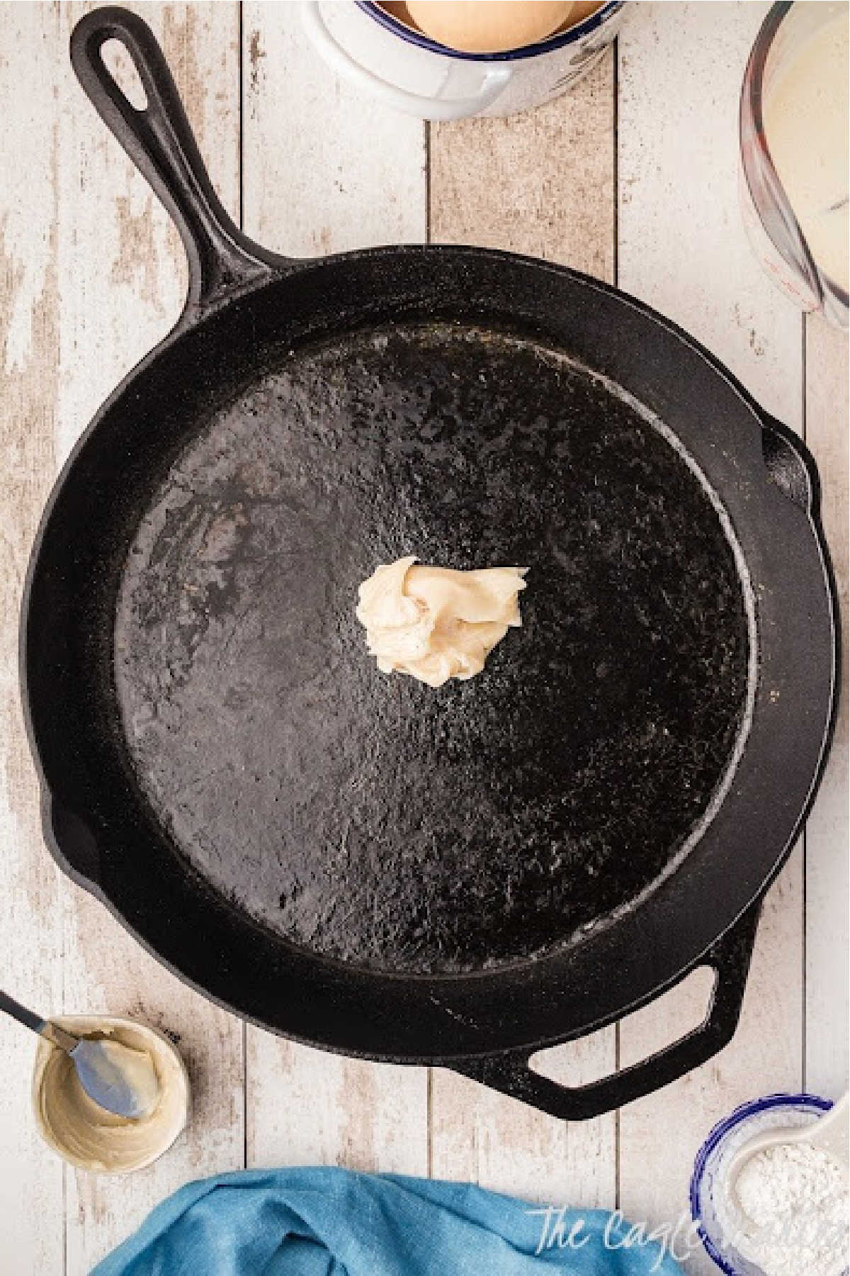 A black cast iron skillet with some bacon grease in the middle waiting to be melted.