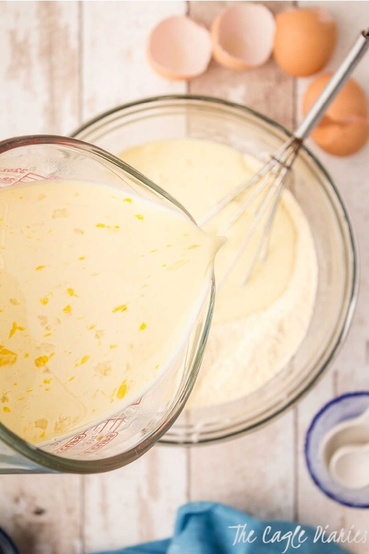 Wet batter being poured into a bowl with dry ingredients to make cornbread.