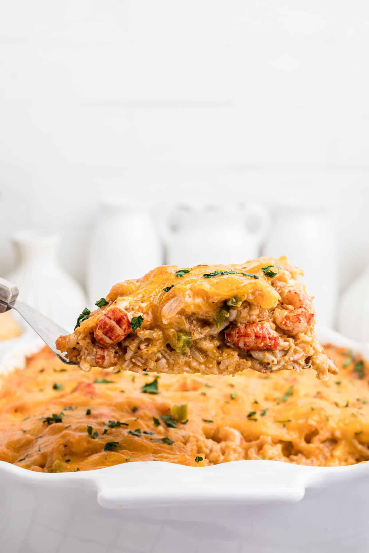 A piece of crawfish casserole being lifted out of a casserole dish.