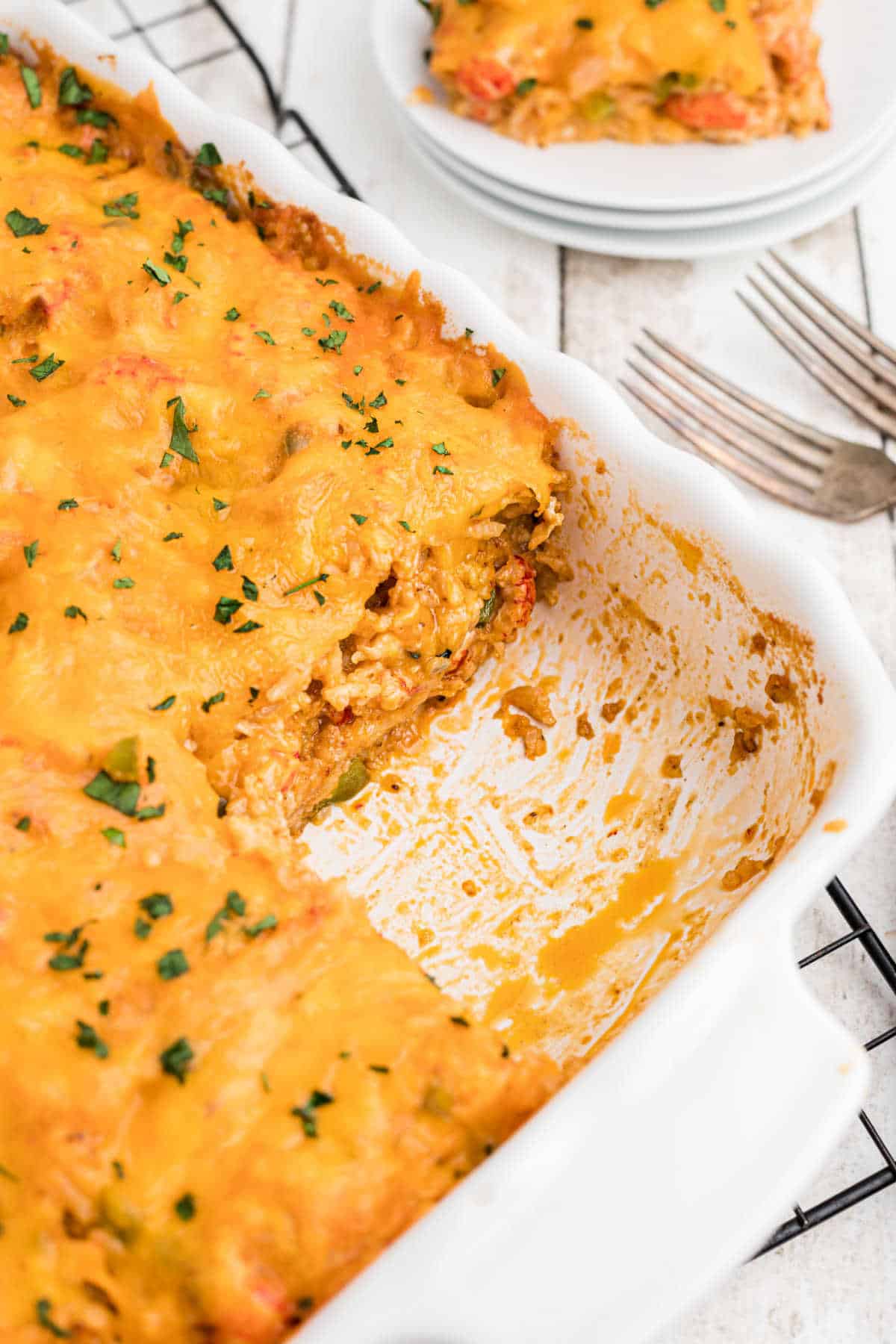 A casserole dish with crawfish casserole with a piece missing.