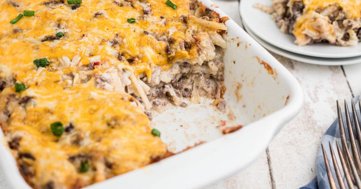 close up of a baking dish with hamburger hashbrown casserole with a scoop missing.