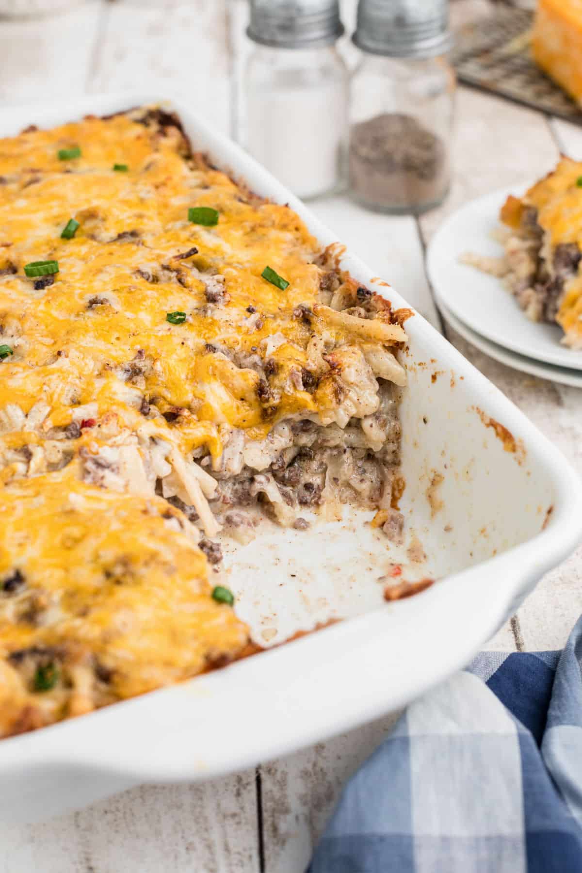 Side shot of a hamburger hashbrown casserole recipe in a dish with a scoop missing.