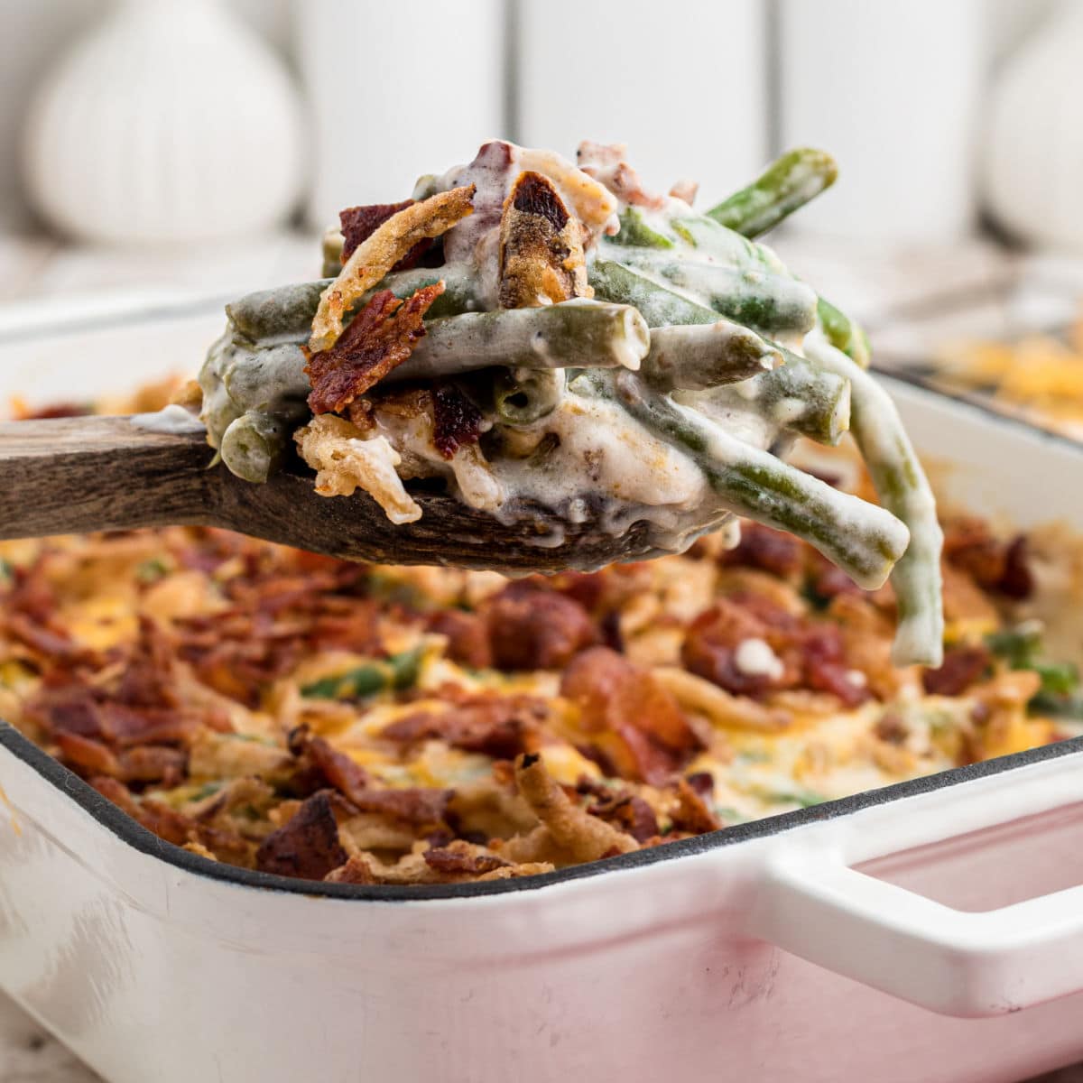 A scoop of loaded green bean casserole being lifted out of the dish.