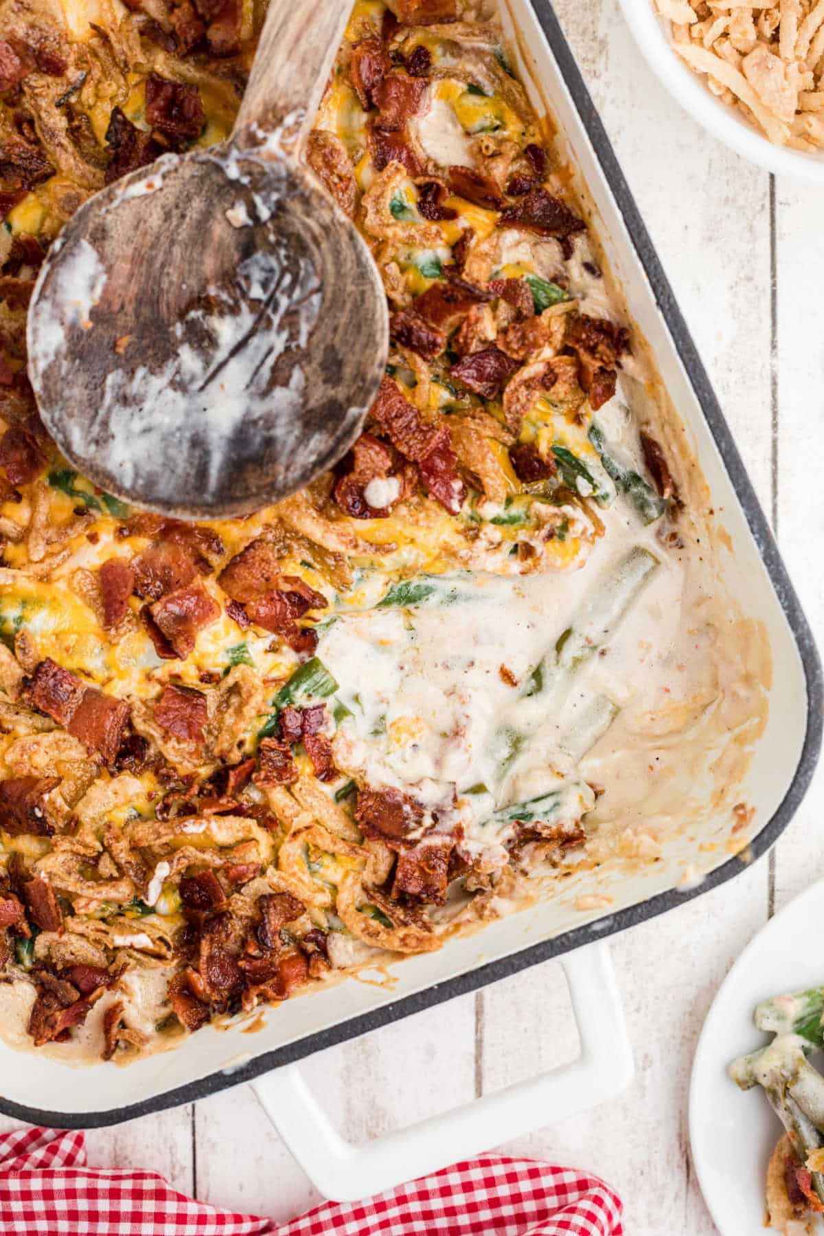 Overhead shot of a casserole dish with loaded green bean casserole in it, a scoop missing.