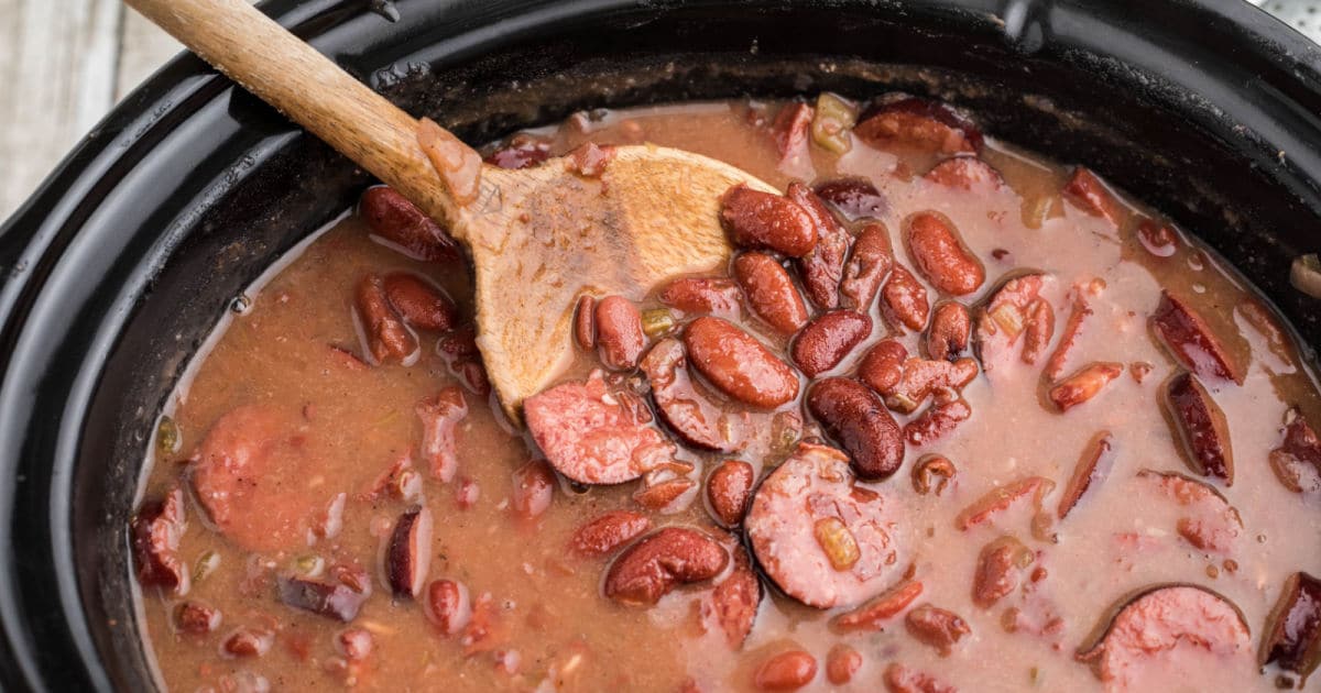 Close up of a slow cooker Cajun red beans and rice recipe with a spoon digging in.