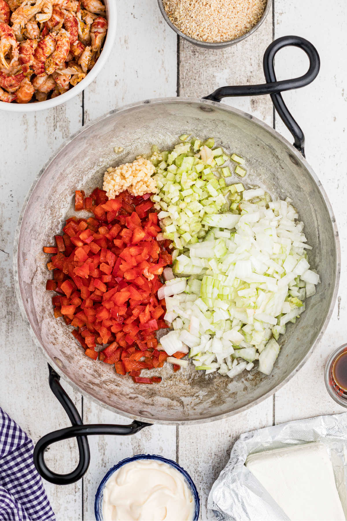 A skillet filled with onions, peppers, celery and garlic.
