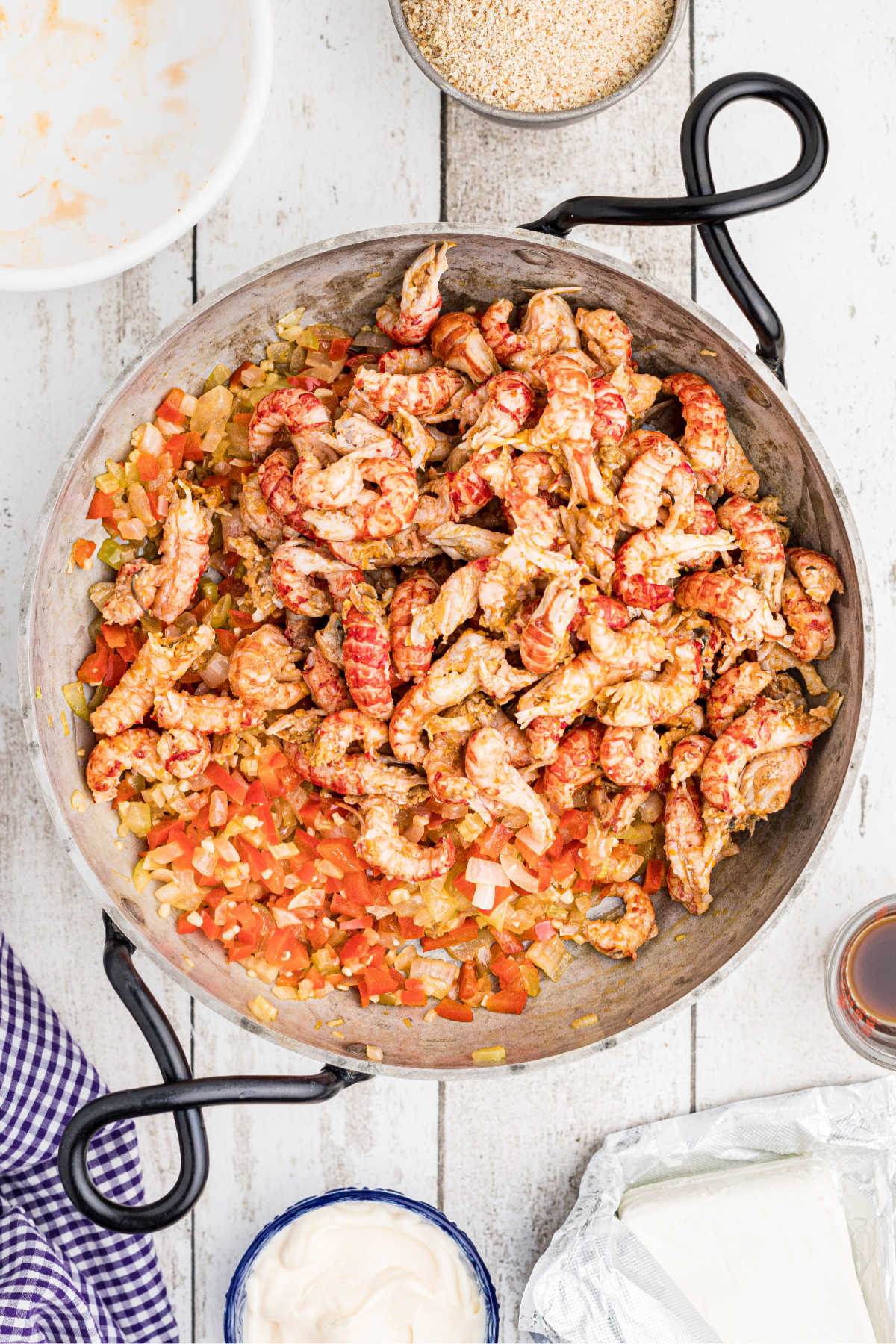 Peeled crawfish tails in a skillet added to veggies.