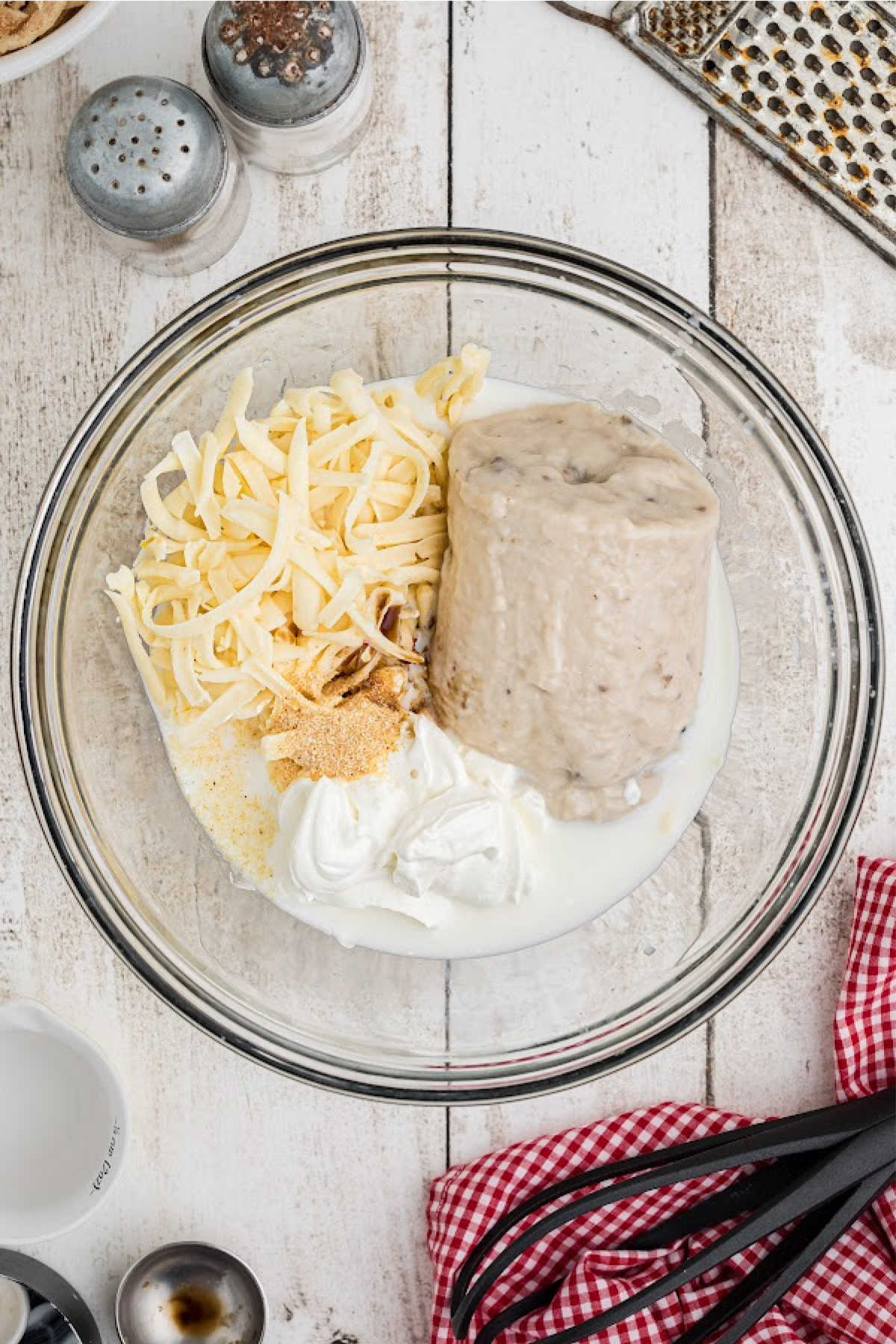 A mixing bowl with mushrooms soup, cheese and milk.