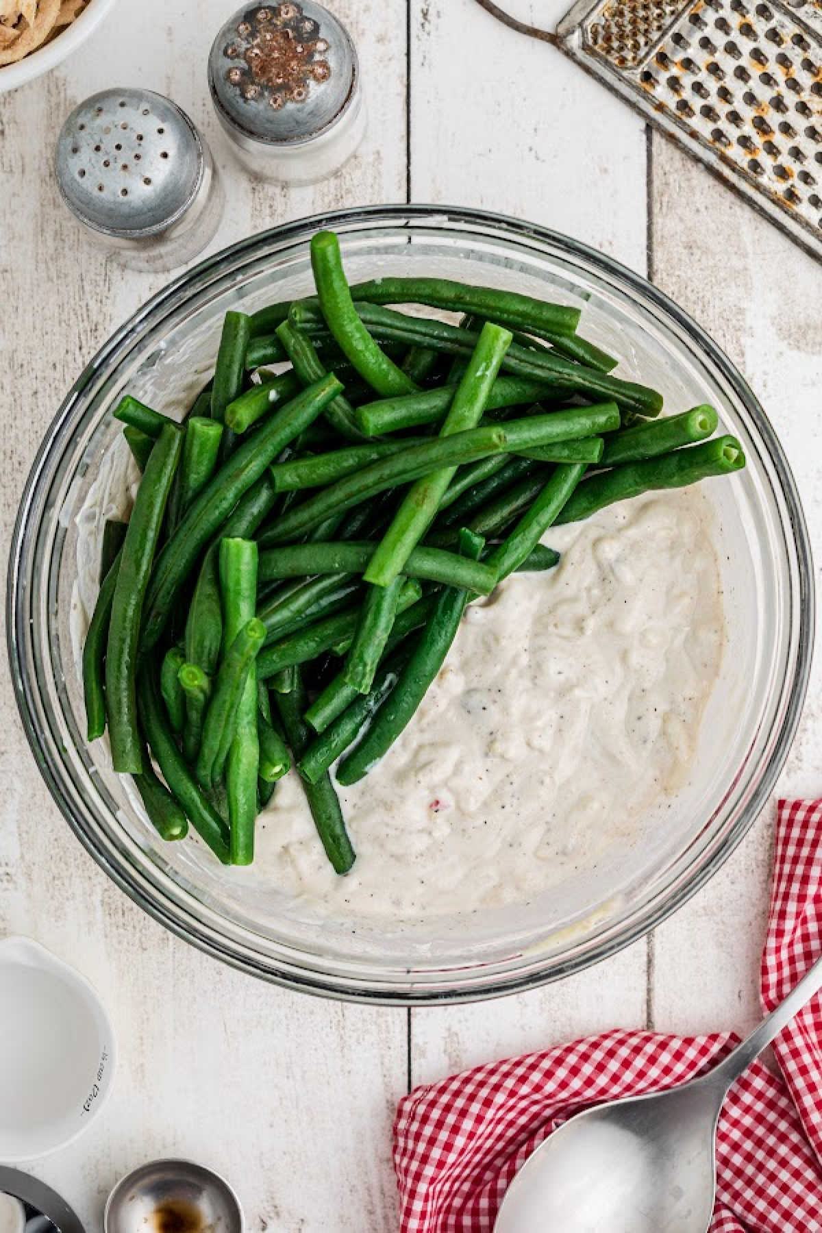 A mixing bowl with green beans and a delicious sauce waiting to be mixed.
