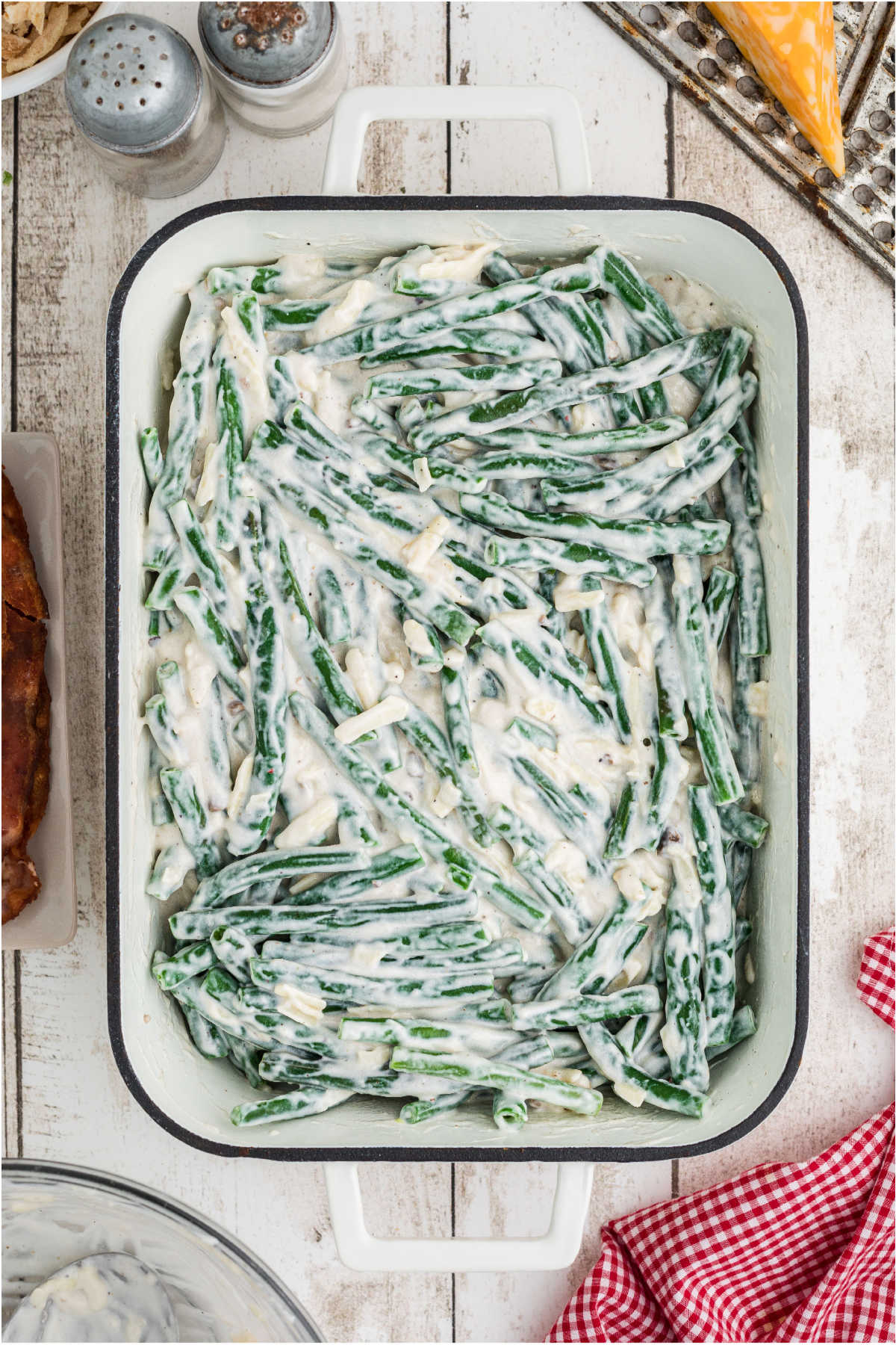 A baking dish filled with green beans and sauce waiting to be baked.