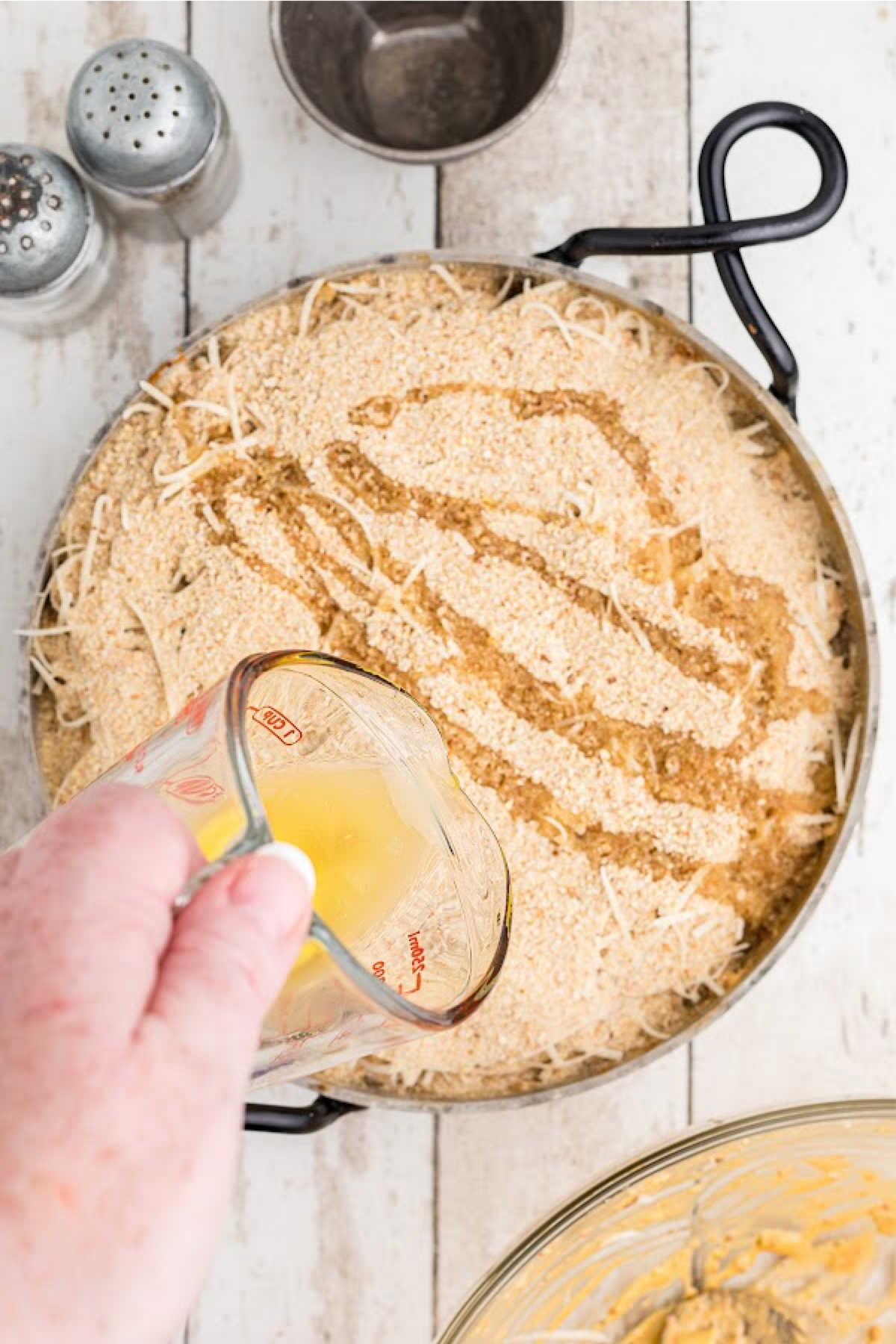 Melted butter being poured over a skillet of crawfish dip.