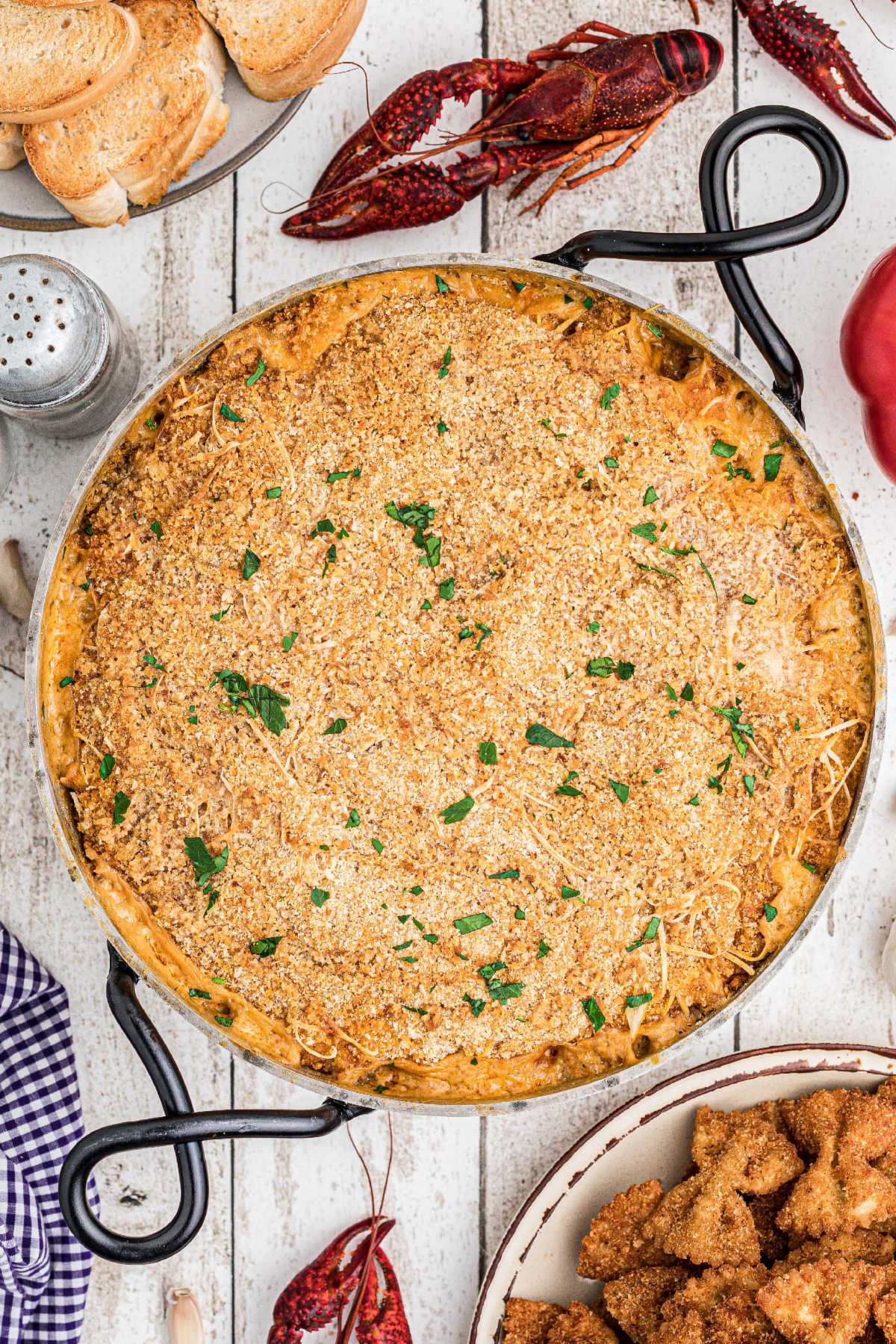 A baked crawfish dip with chopped parsley sprinkled on top.