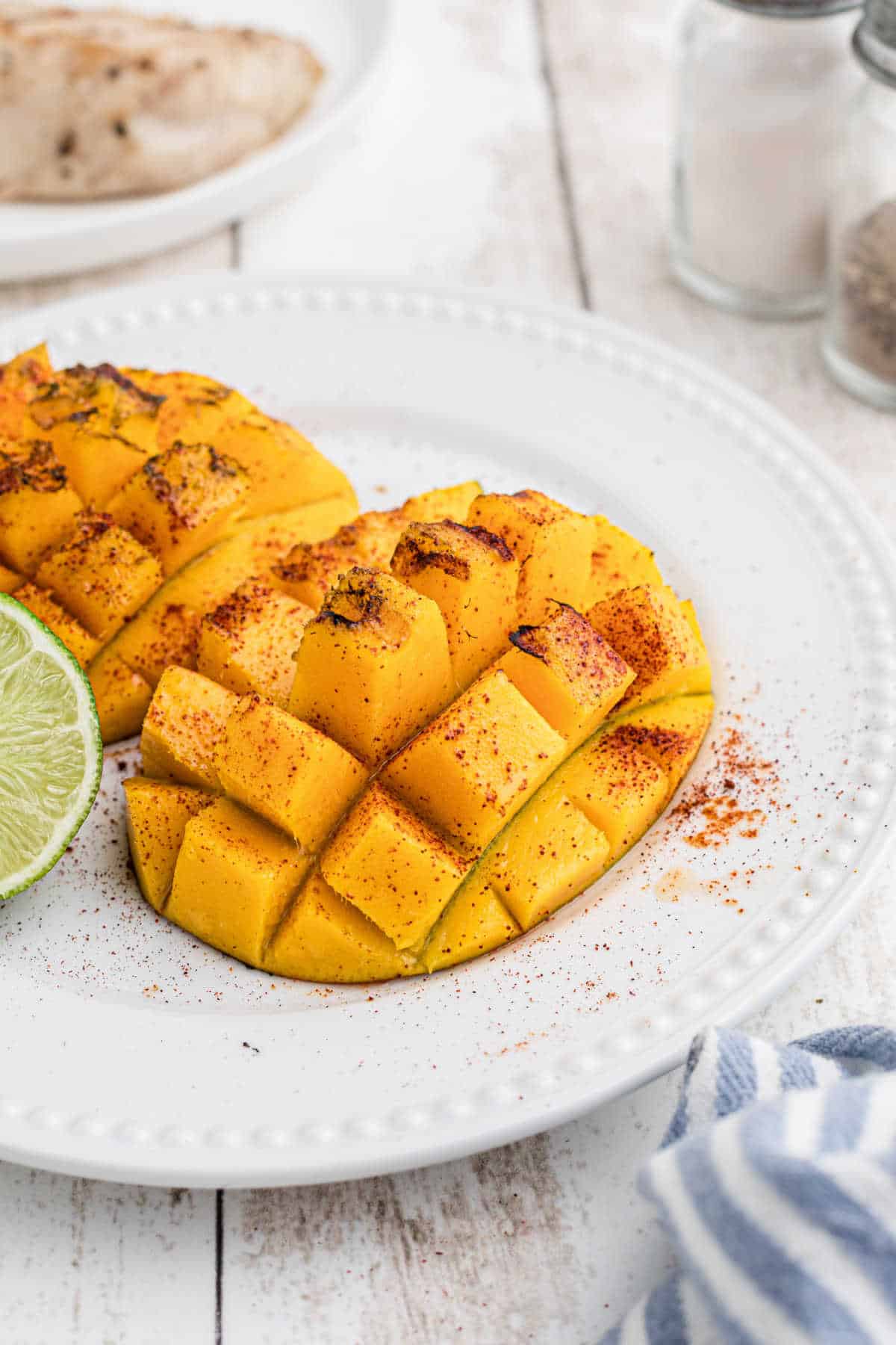 Grilled mango on a plate with seasoning.