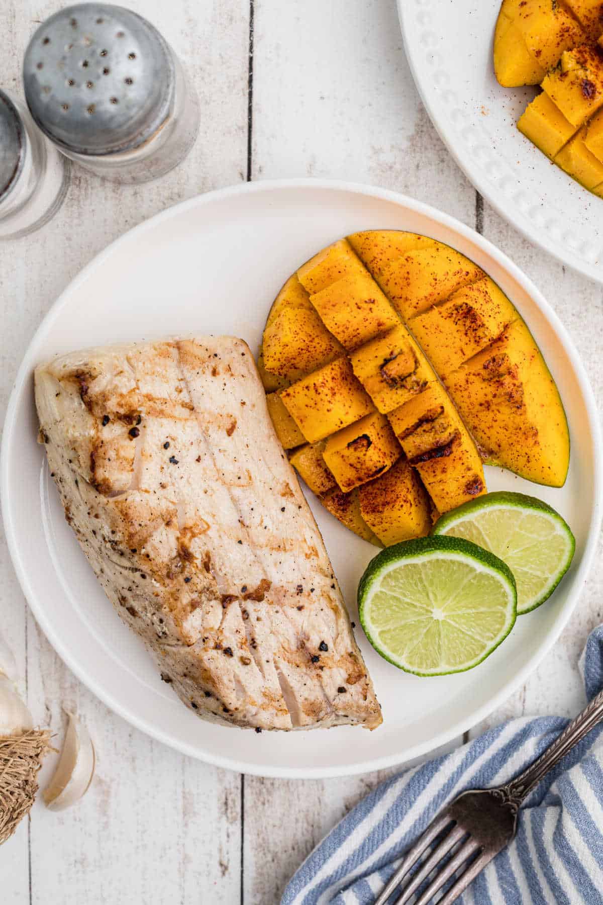 Overhead shot of a piece of grilled mango and grilled cobia on a plate.