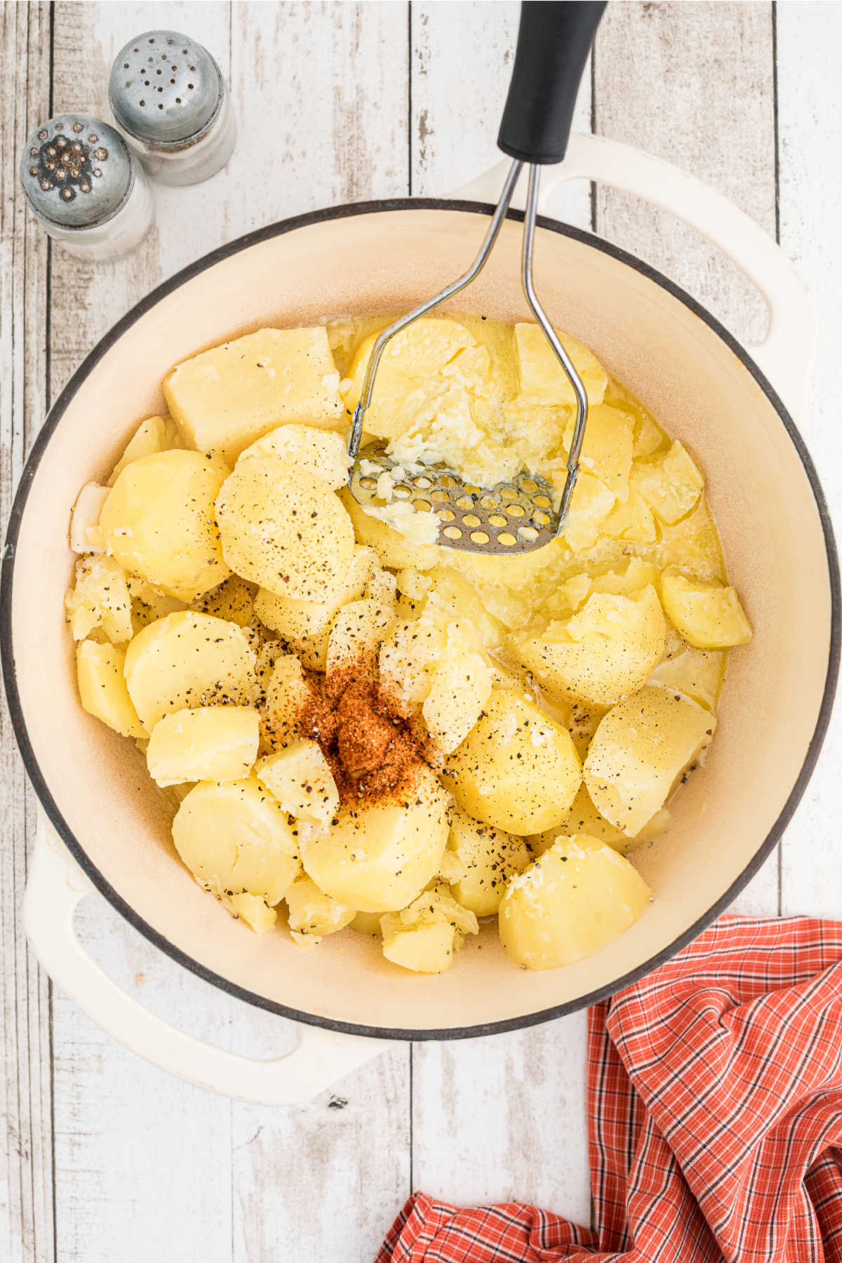 Potatoes about to be mashed with seasoning in a large pot.