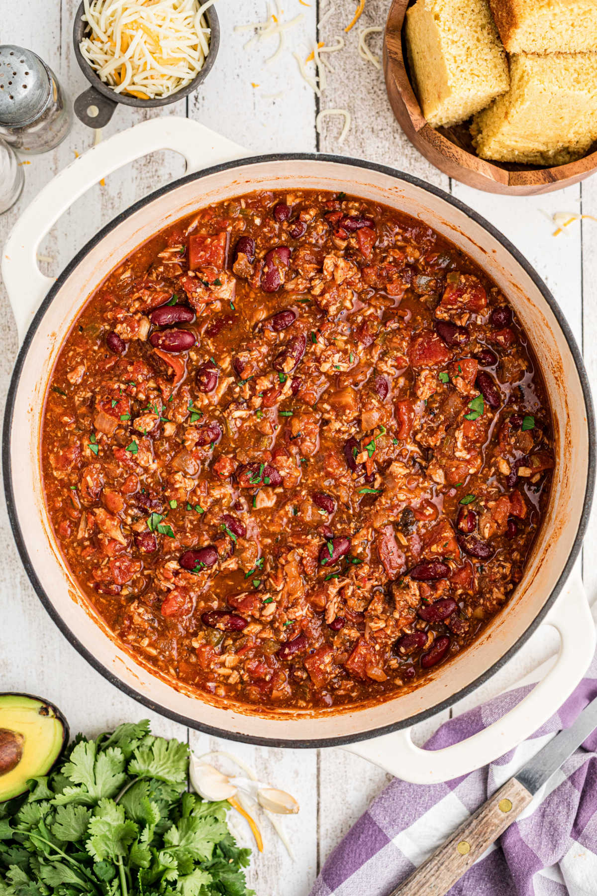 Overhead shot of a Dutch Oven turkey chili with some cornbread and avocado.