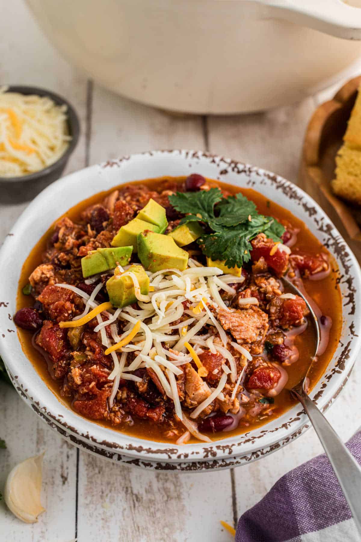 Side view of a bowl of Dutch Oven Turkey Chili with a spoon digging in.