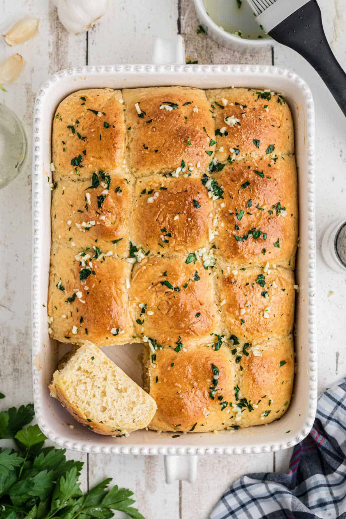 Garlic butter rolls in a baking dish, from overhead. One roll standing on its side.