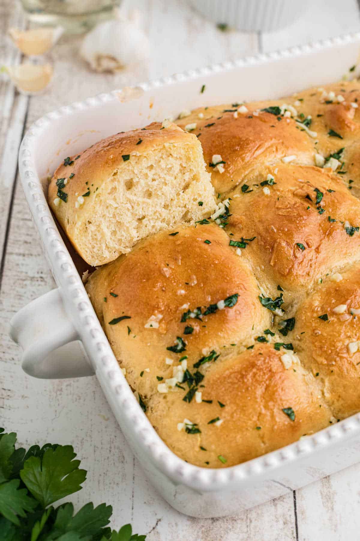 Garlic butter rolls in a baking dish, a corner shot. One corner roll standing on its side.