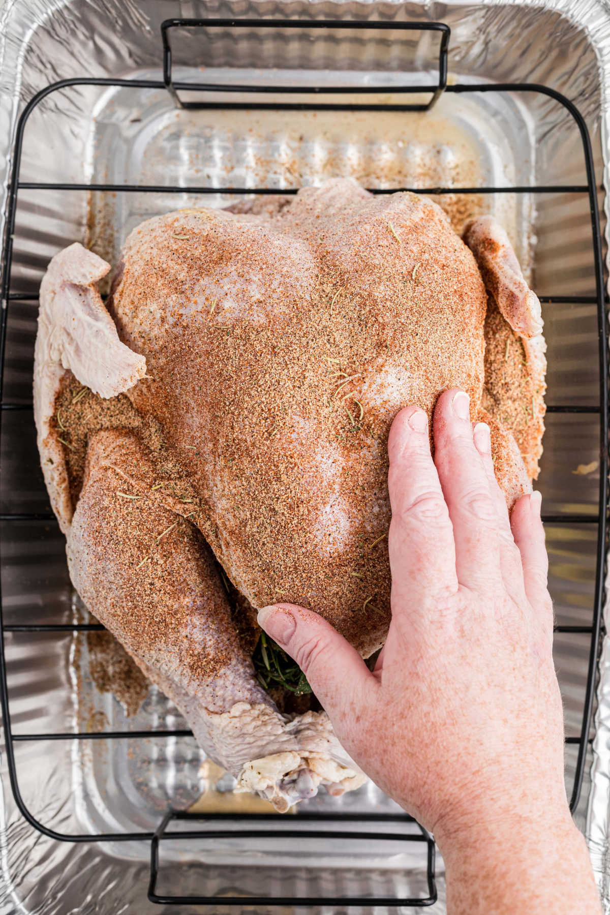 Rubbing a turkey seasoning blend all over the bird.