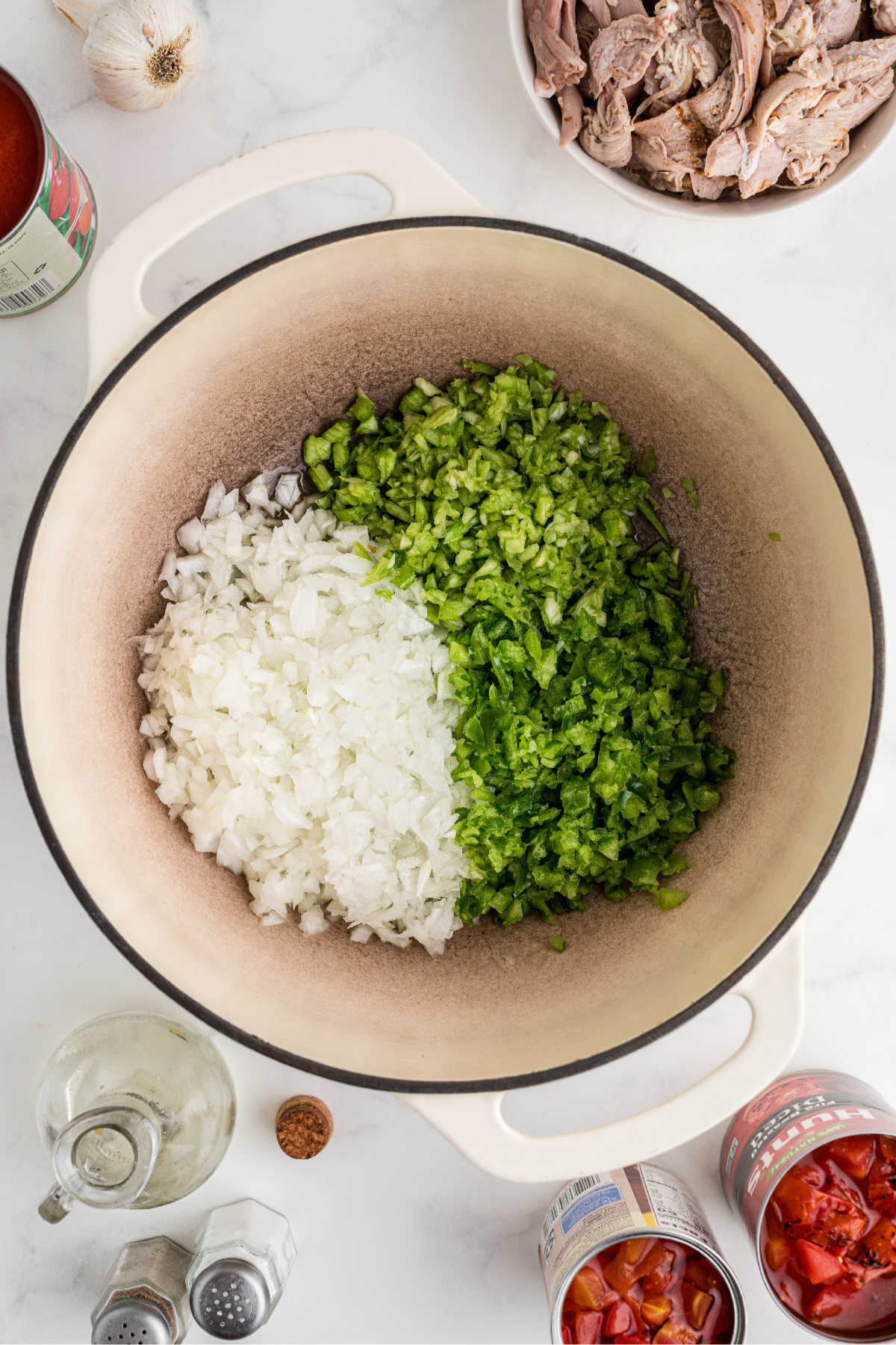 A Dutch oven with onions, bell peppers and celery about to be cooked.