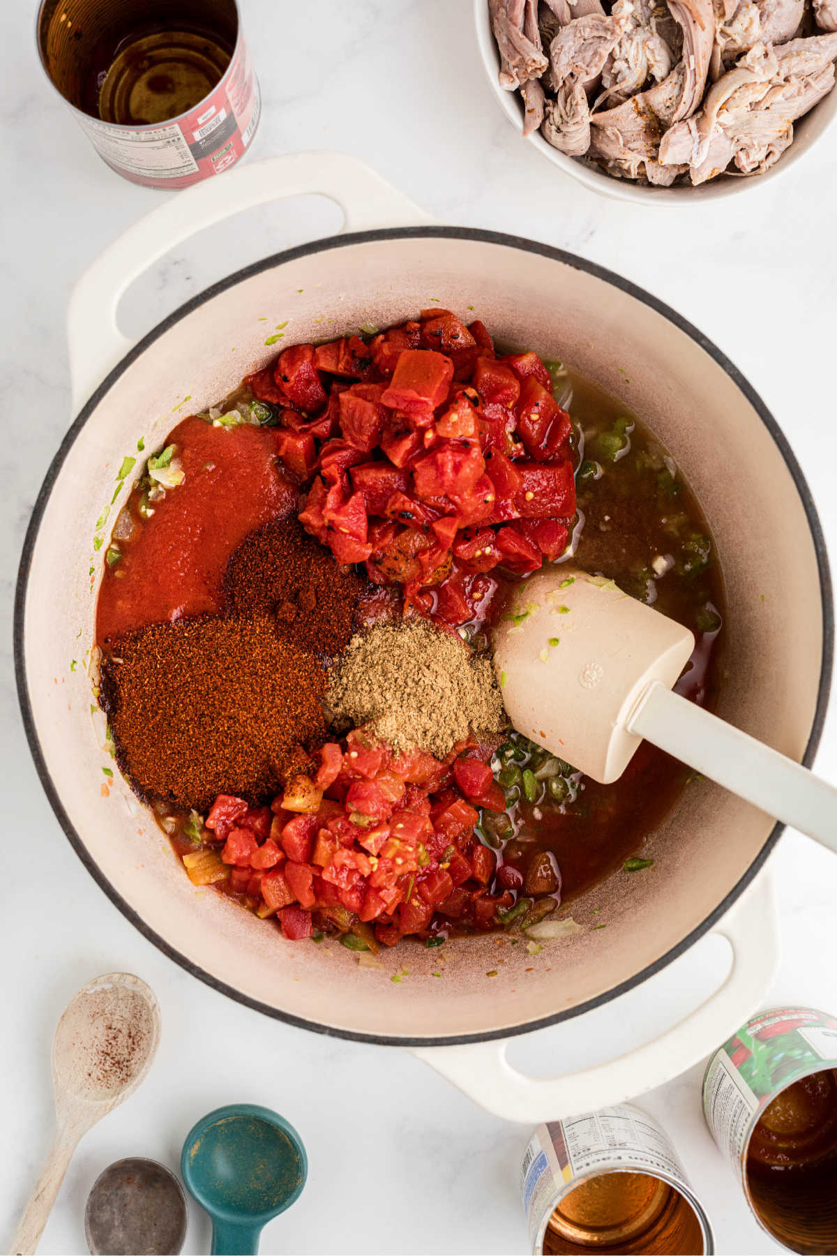 Tomatoes and seasonings added to a Dutch oven.