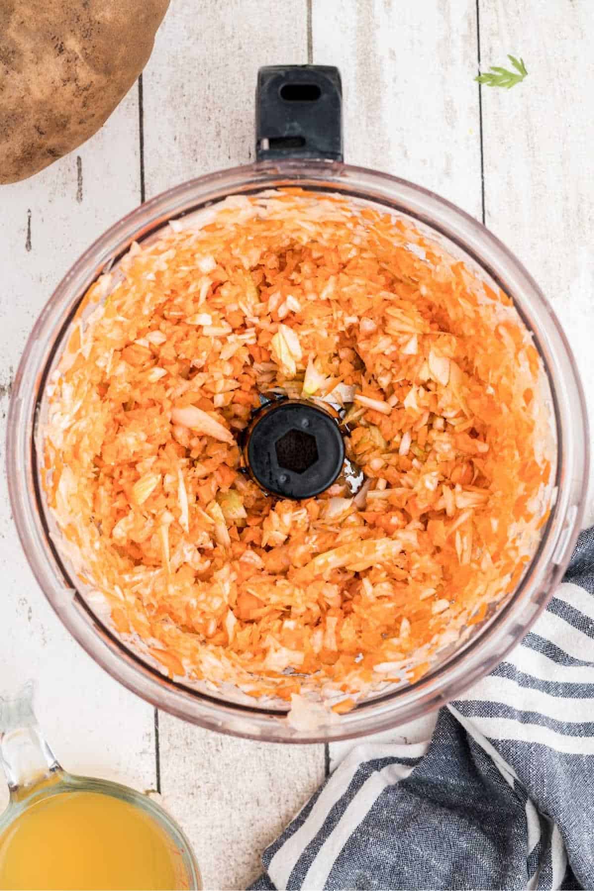 Carrots, onion and celery being diced in a food processor.