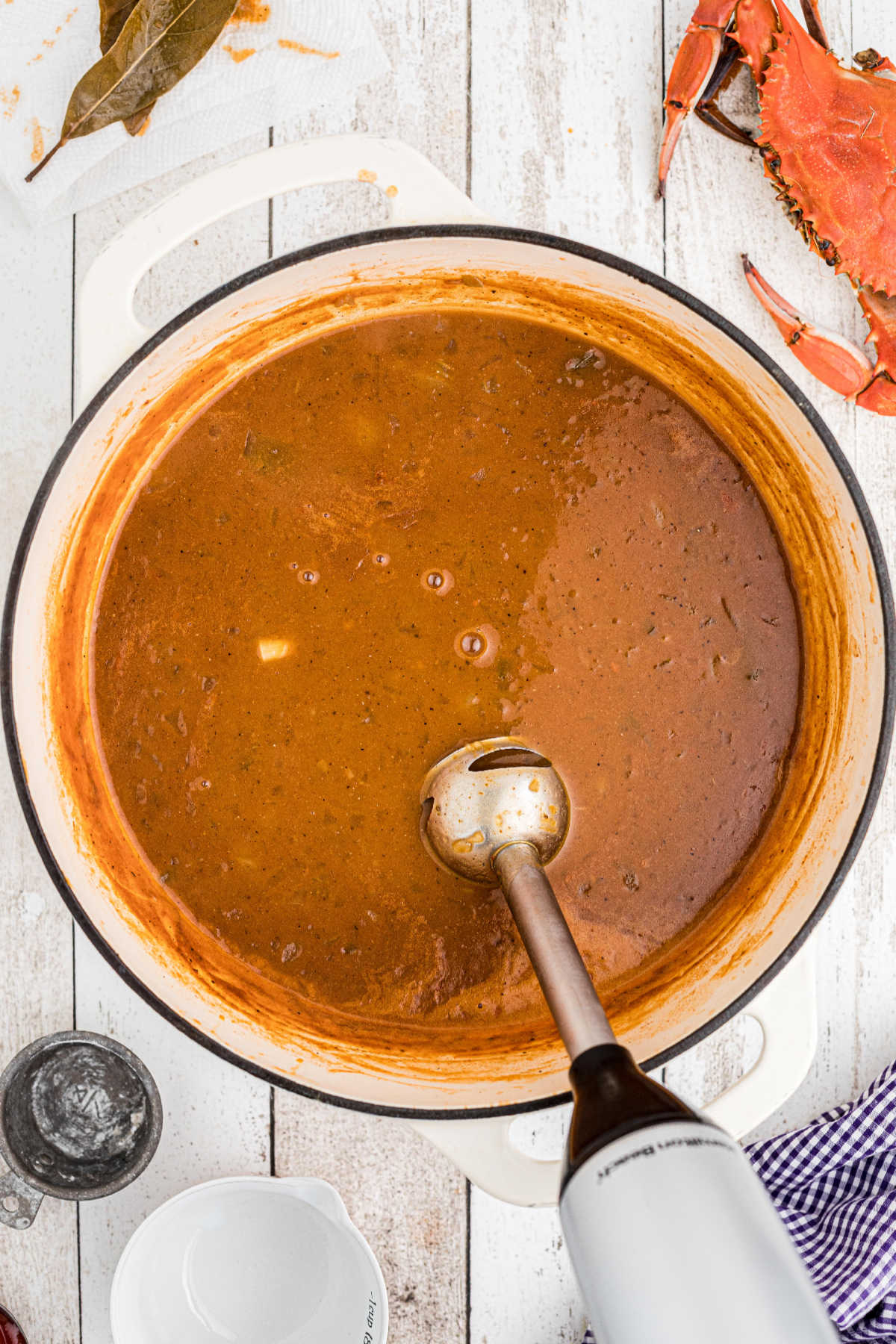 A stick blender being used in a large Dutch oven full of soup.