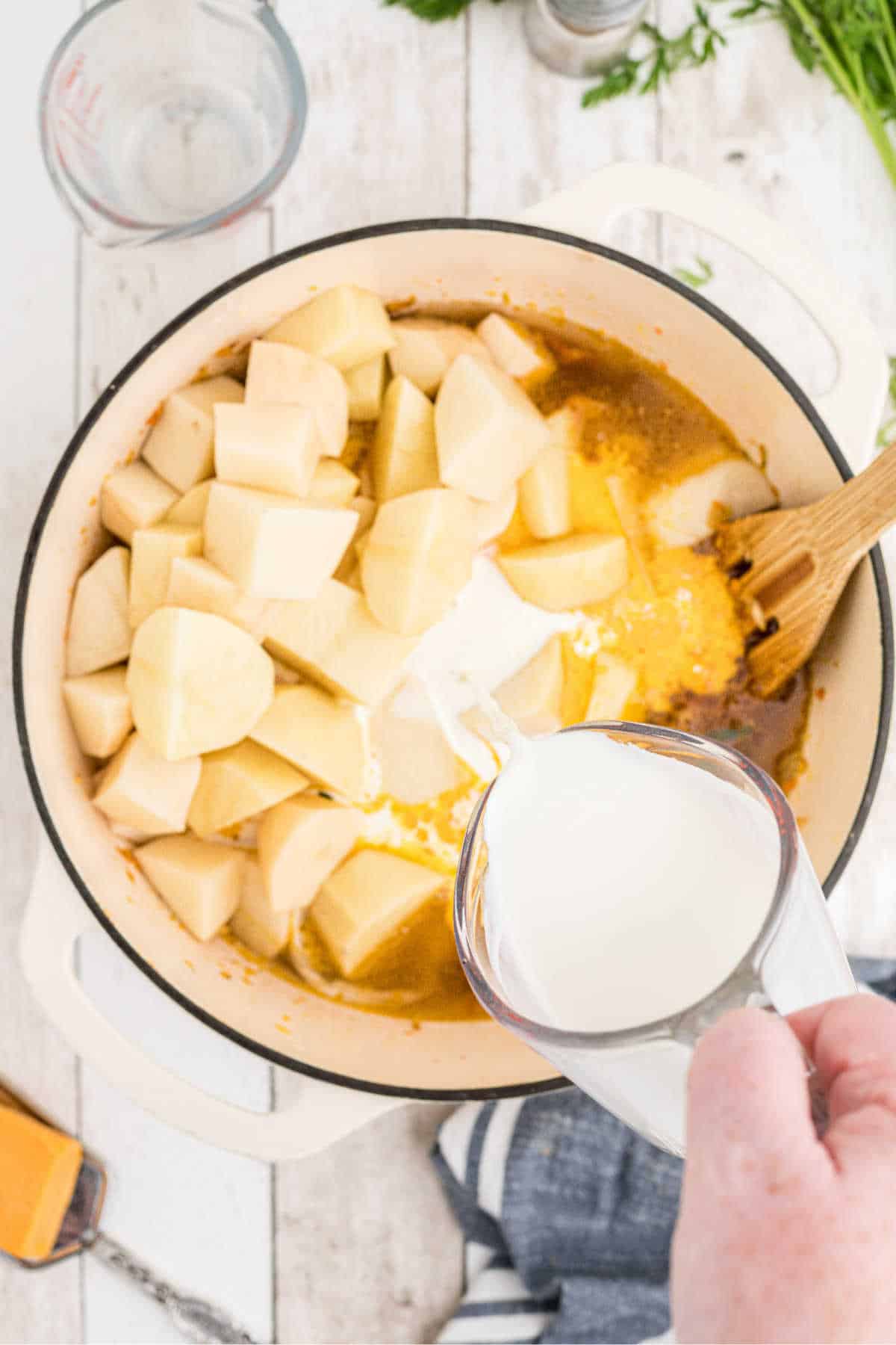 Cream being poured into a large Dutch oven.