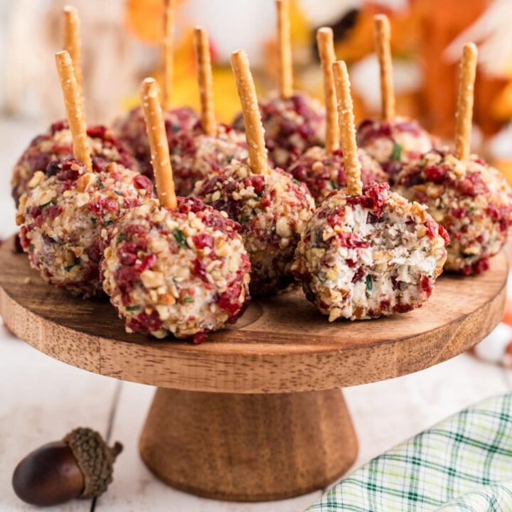 A cake stand full of cranberry pecan cheese ball bites with a bite taken out of one.