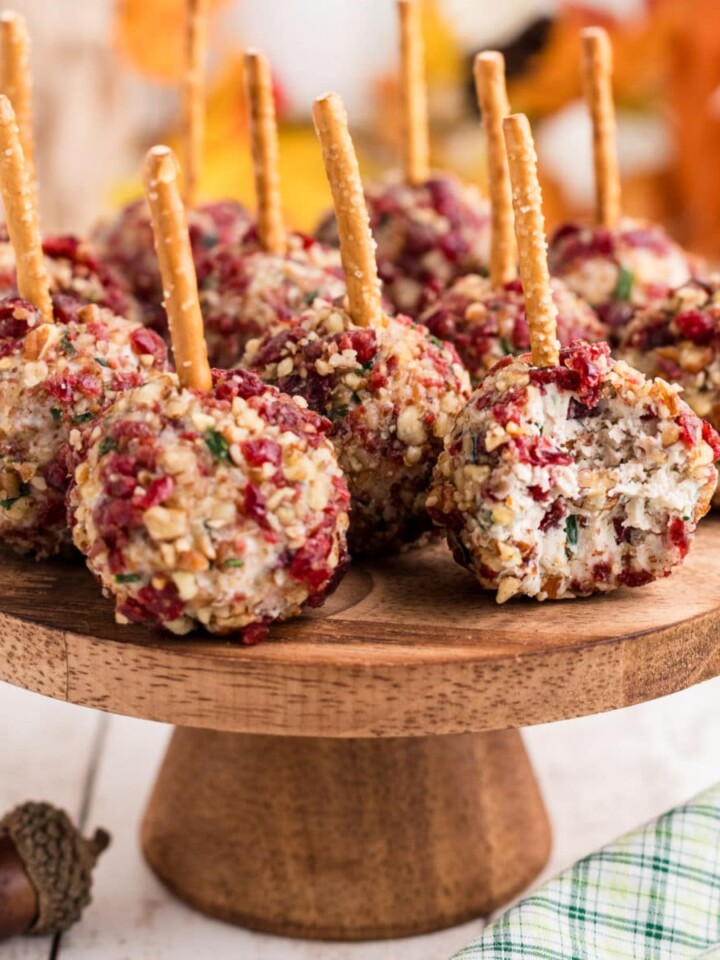 A cake stand full of cranberry pecan cheese ball bites with a bite taken out of one.