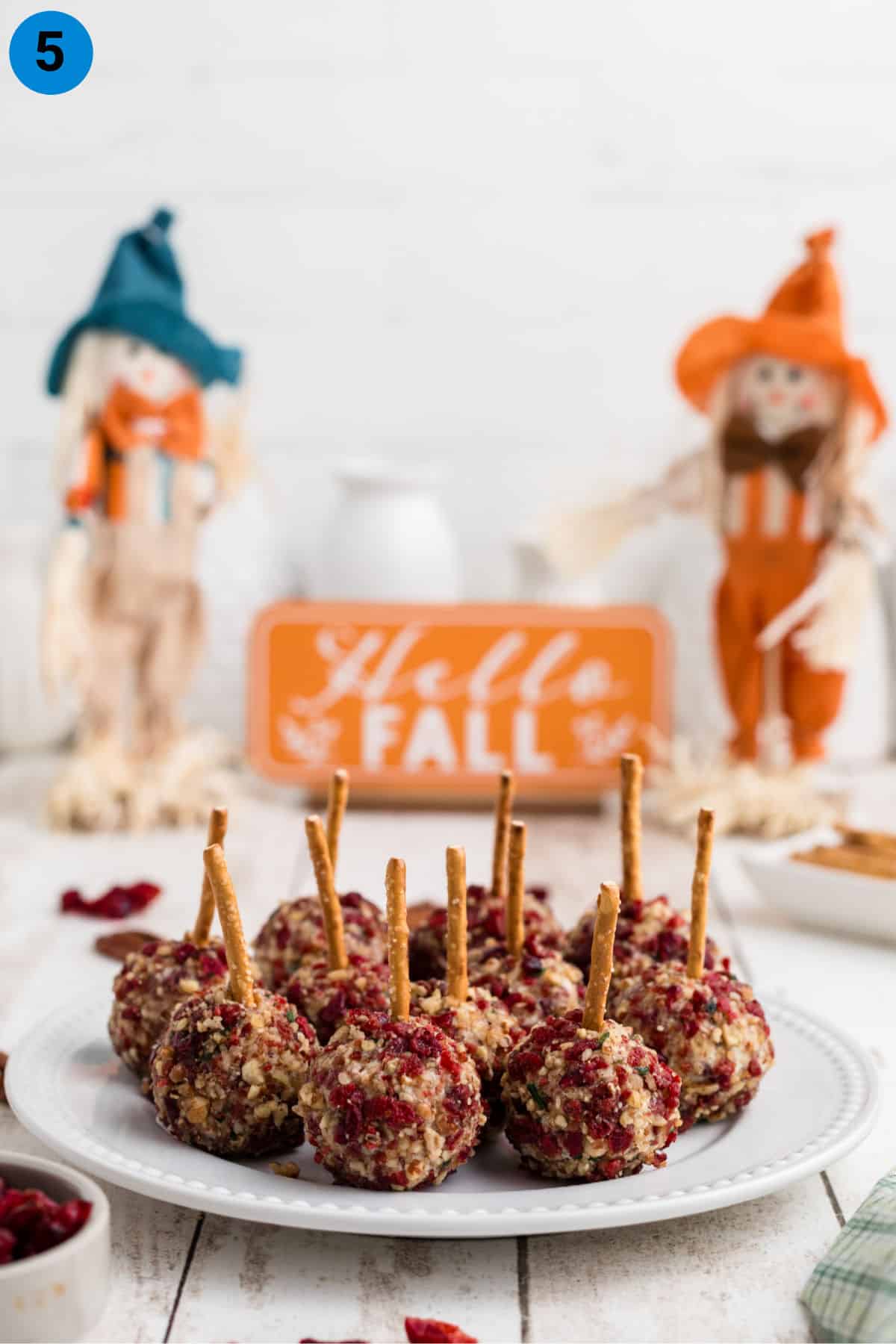 A plate full of cranberry pecan cheese ball bites, with some fall decorations in the back.