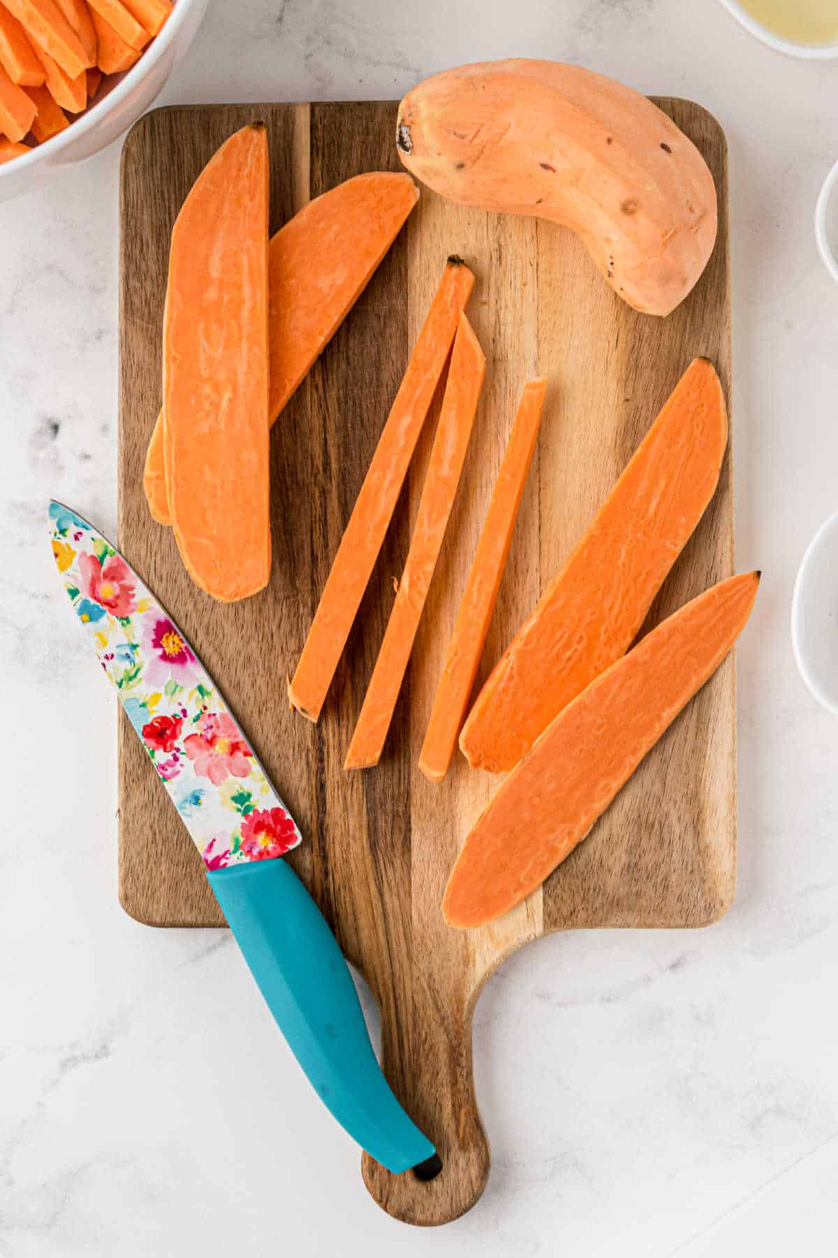Sweet Potatoes cut into sticks with a knife.