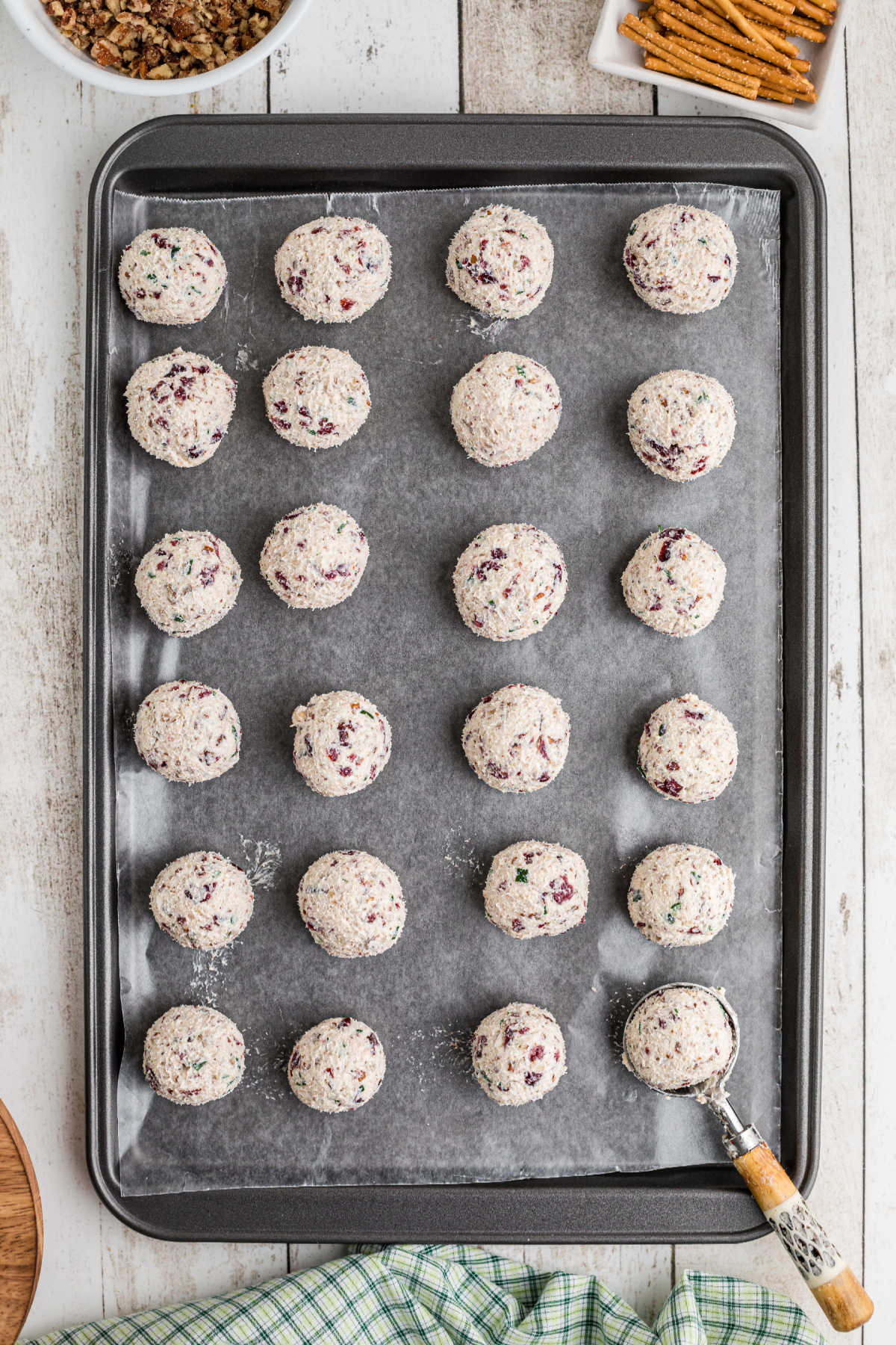 A baking sheet with rolled up cranberry pecan cheese balls.