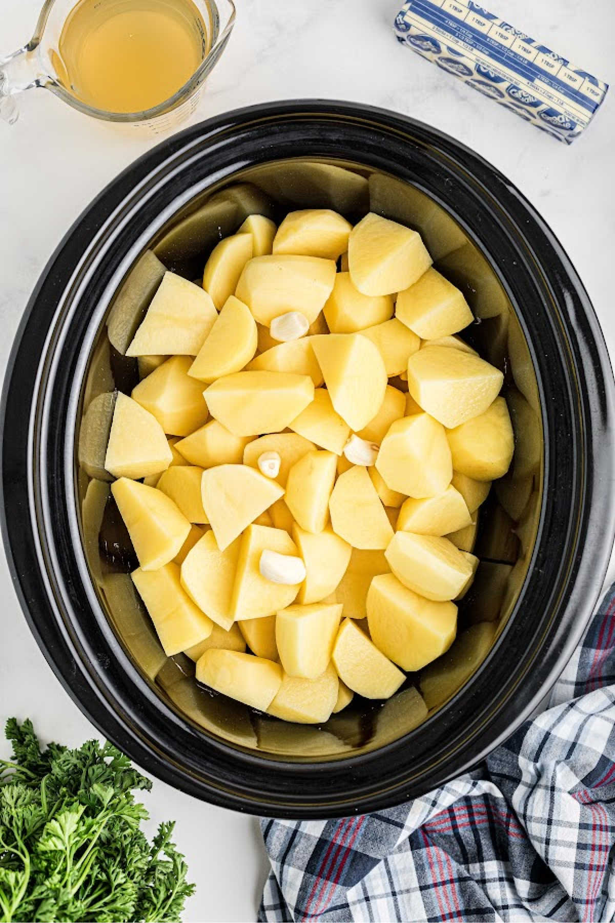 Chopped potatoes added to a large slow cooker.