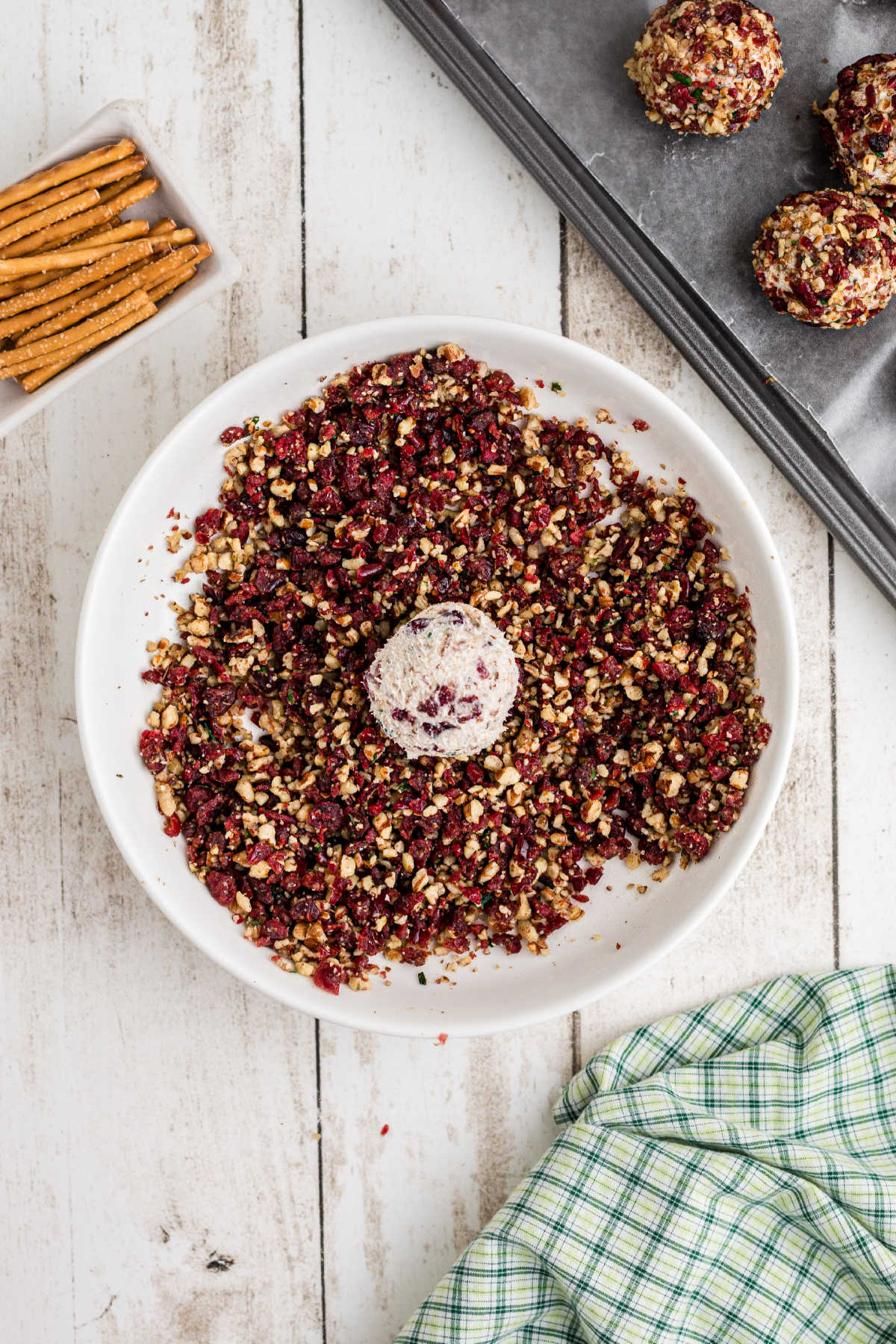 Cheese balls being rolled in chopped pecan mixture.