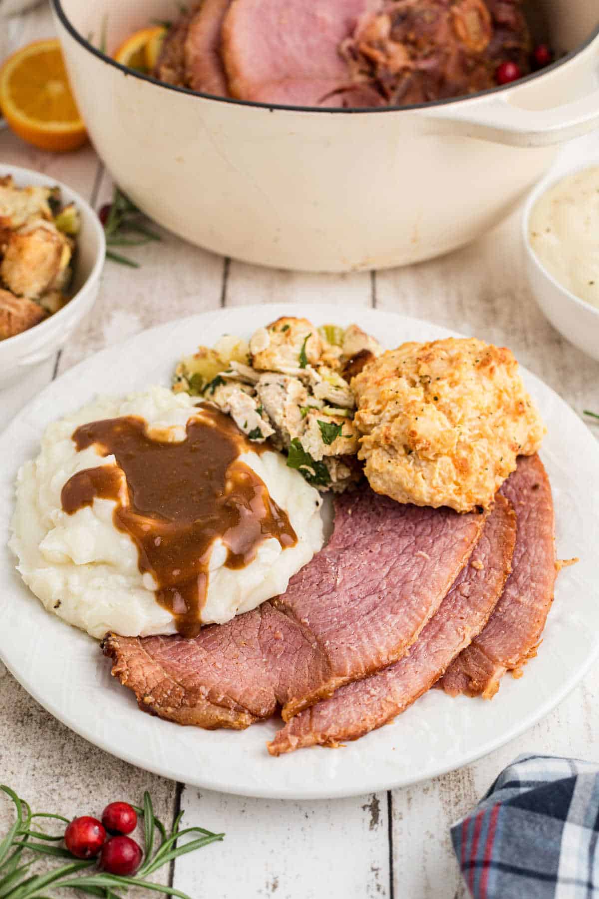 A dished up plate of Dutch Oven Ham with mashed potatoes, stuffing and bread.