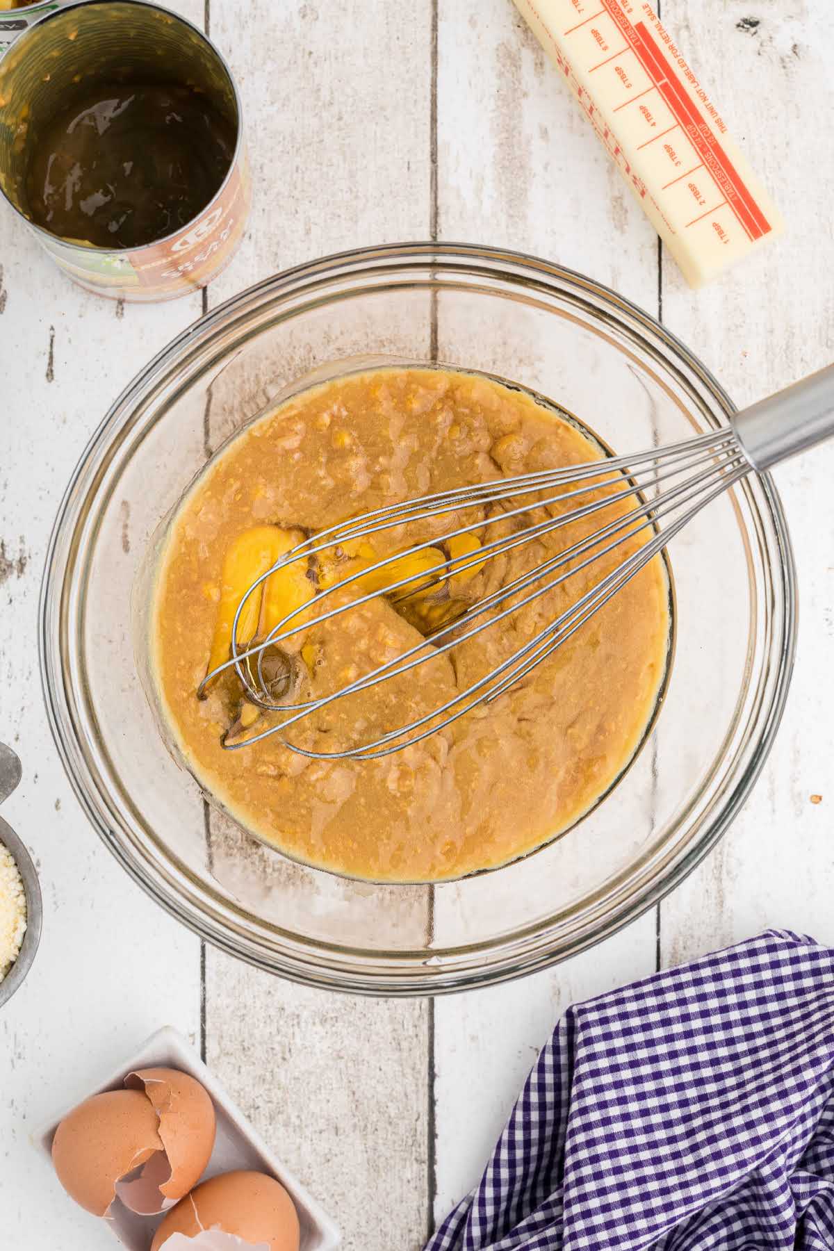 A large mixing bowl with eggs and creamed corn mixed together.