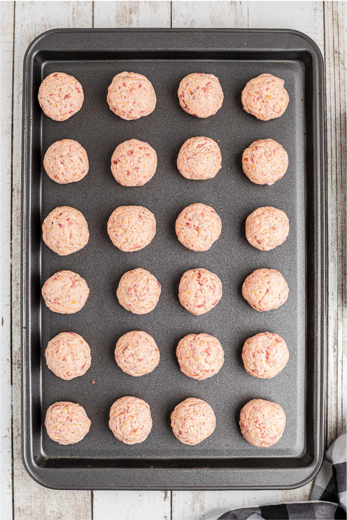 Sausage balls lined up on a baking sheet.